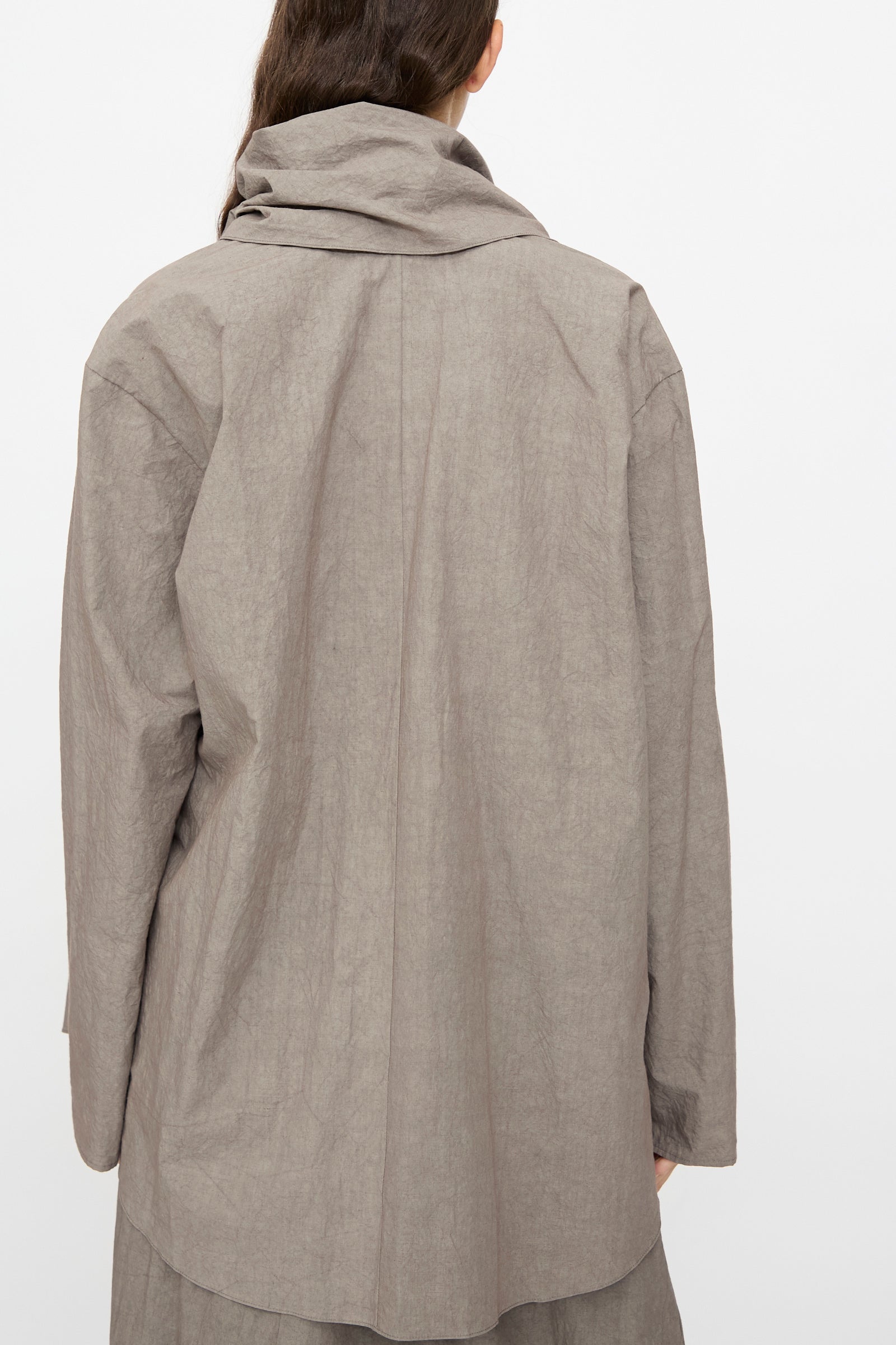 A person is photographed from the back against a plain white background, wearing the Lauren Manoogian Wrap Top in Cinder—a loose-fitting, long sleeve cotton top.