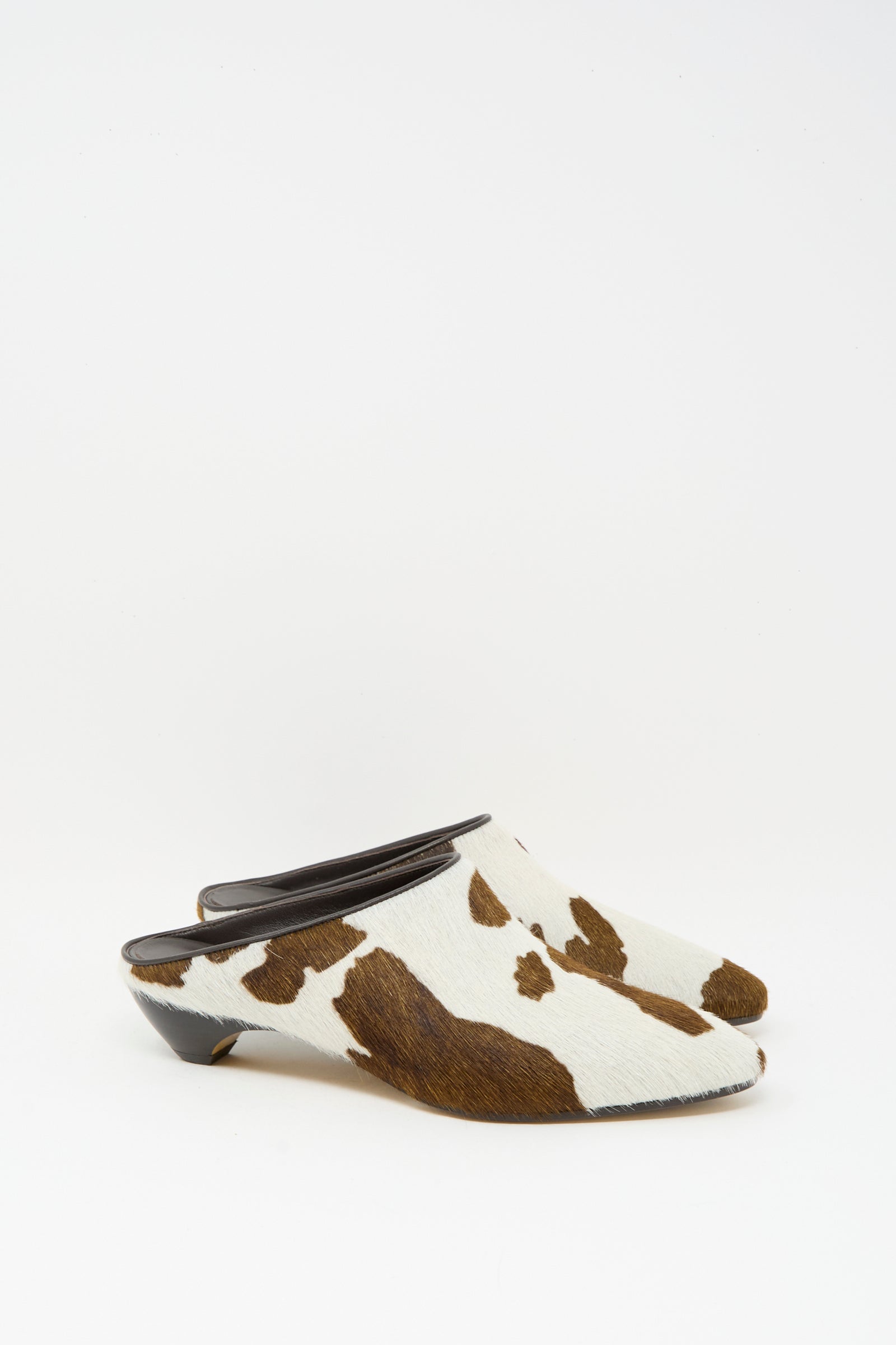 The Le Monde Beryl Allegra Mule in Cow features a low mini heel and calf hair leather upper with a chic brown and white cow print, displayed on a white background.