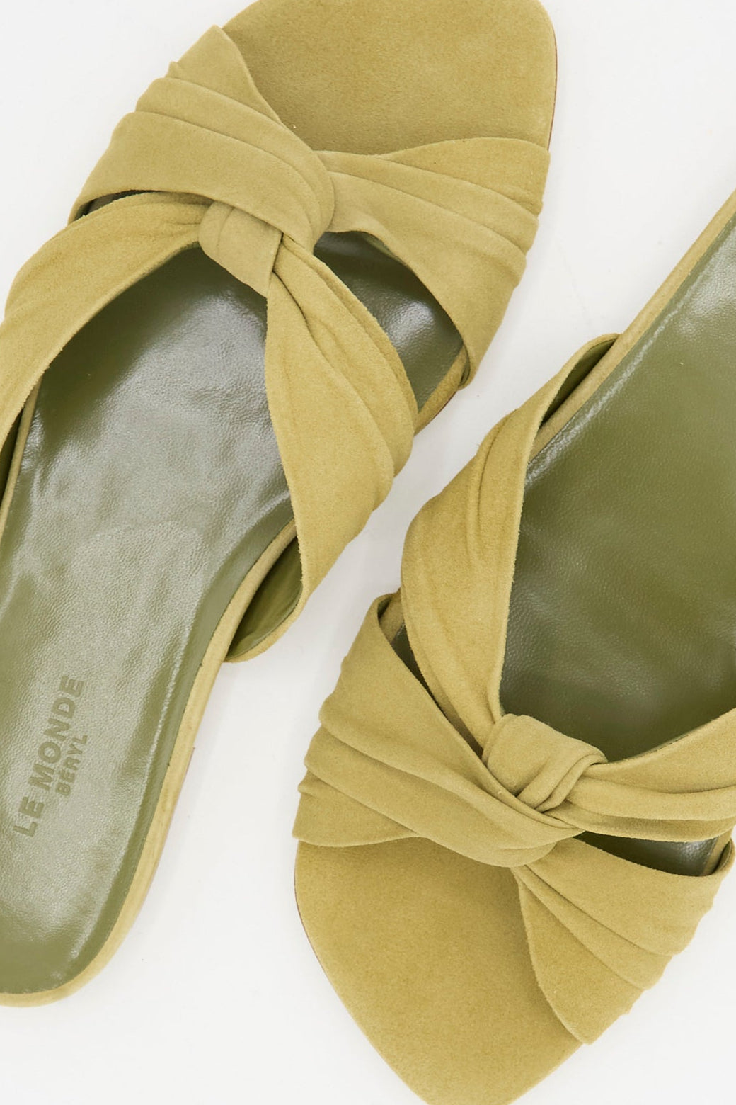 The Antonia Flat in Grey Green by Le Monde Beryl features wide, twisted Italian suede straps and an open-toe design in a light olive hue.