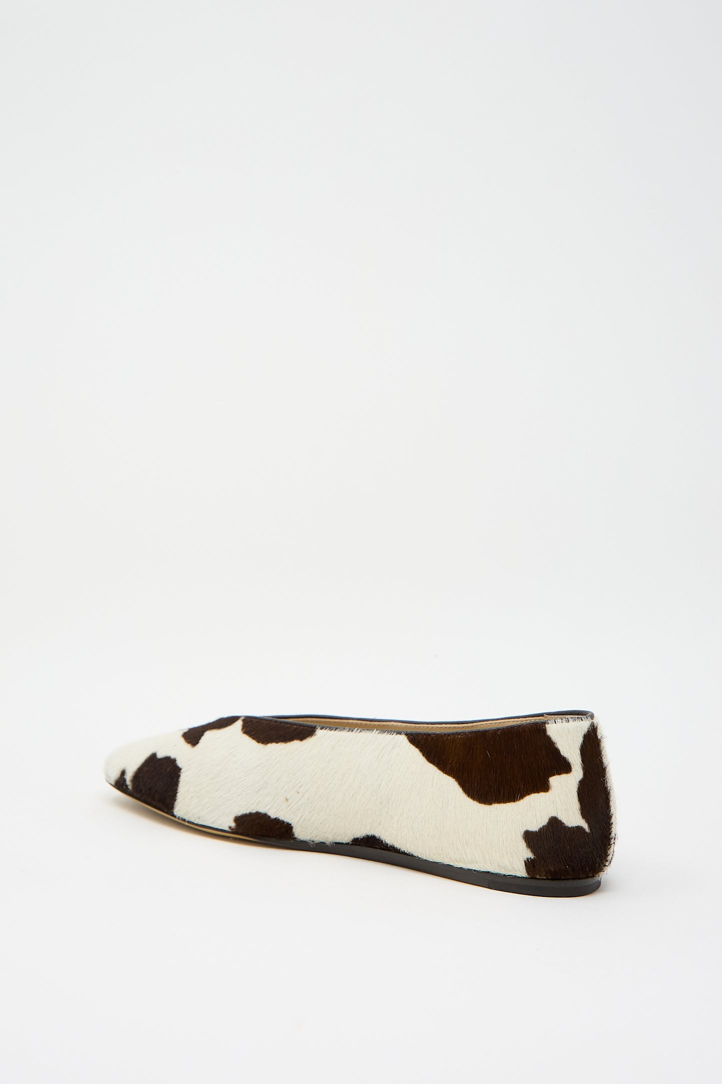 The Calf Hair Regency Slipper in Cow by Le Monde Beryl features a sophisticated brown and white cow print pattern on calf hair, tastefully accented with delicate leather piping.