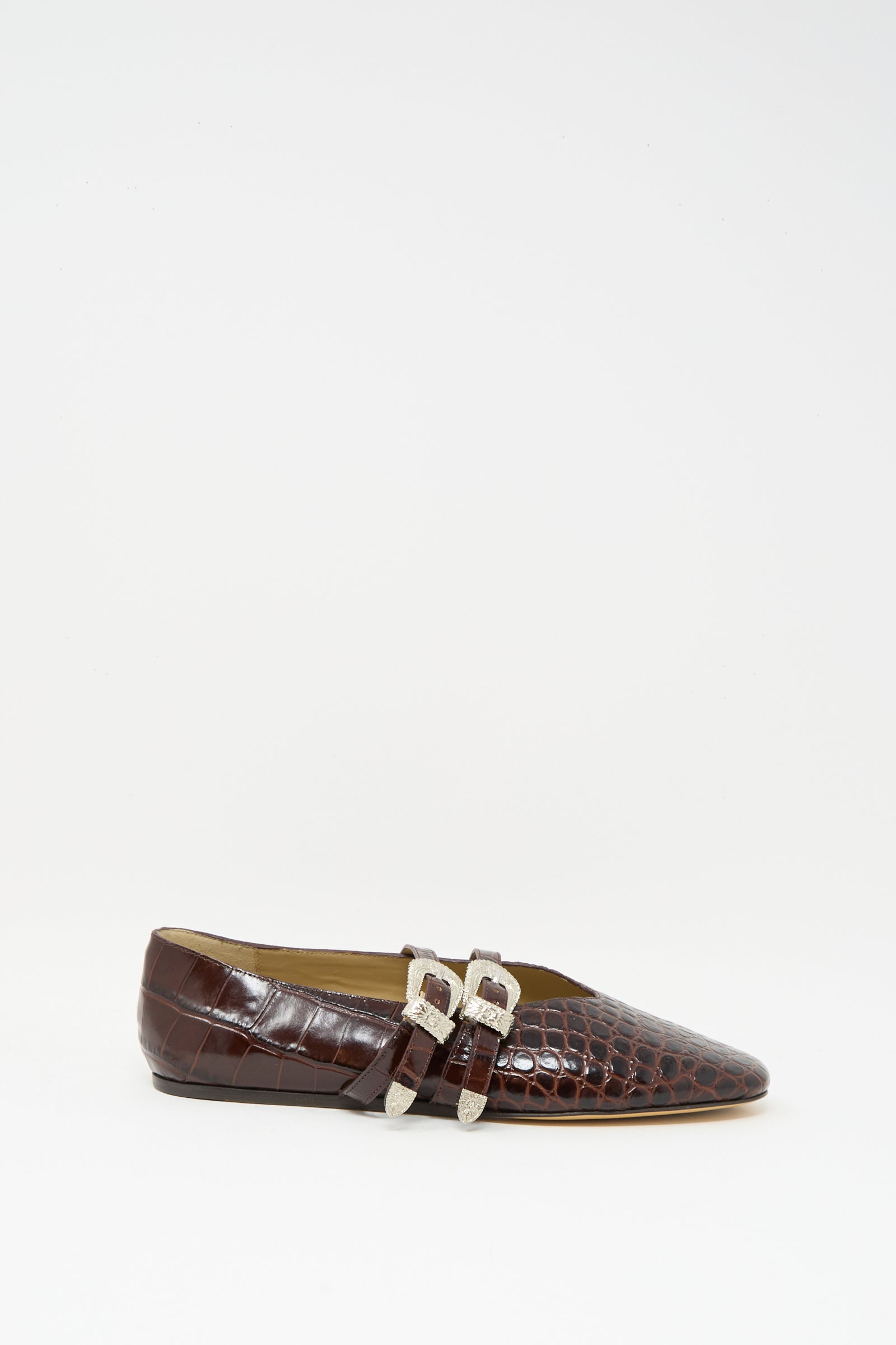 The Claudia Slipper in Coco Brown by Le Monde Beryl is a luxurious calf leather ballet flat with a crocodile pattern and two silver buckles, displayed in profile against a plain white background.