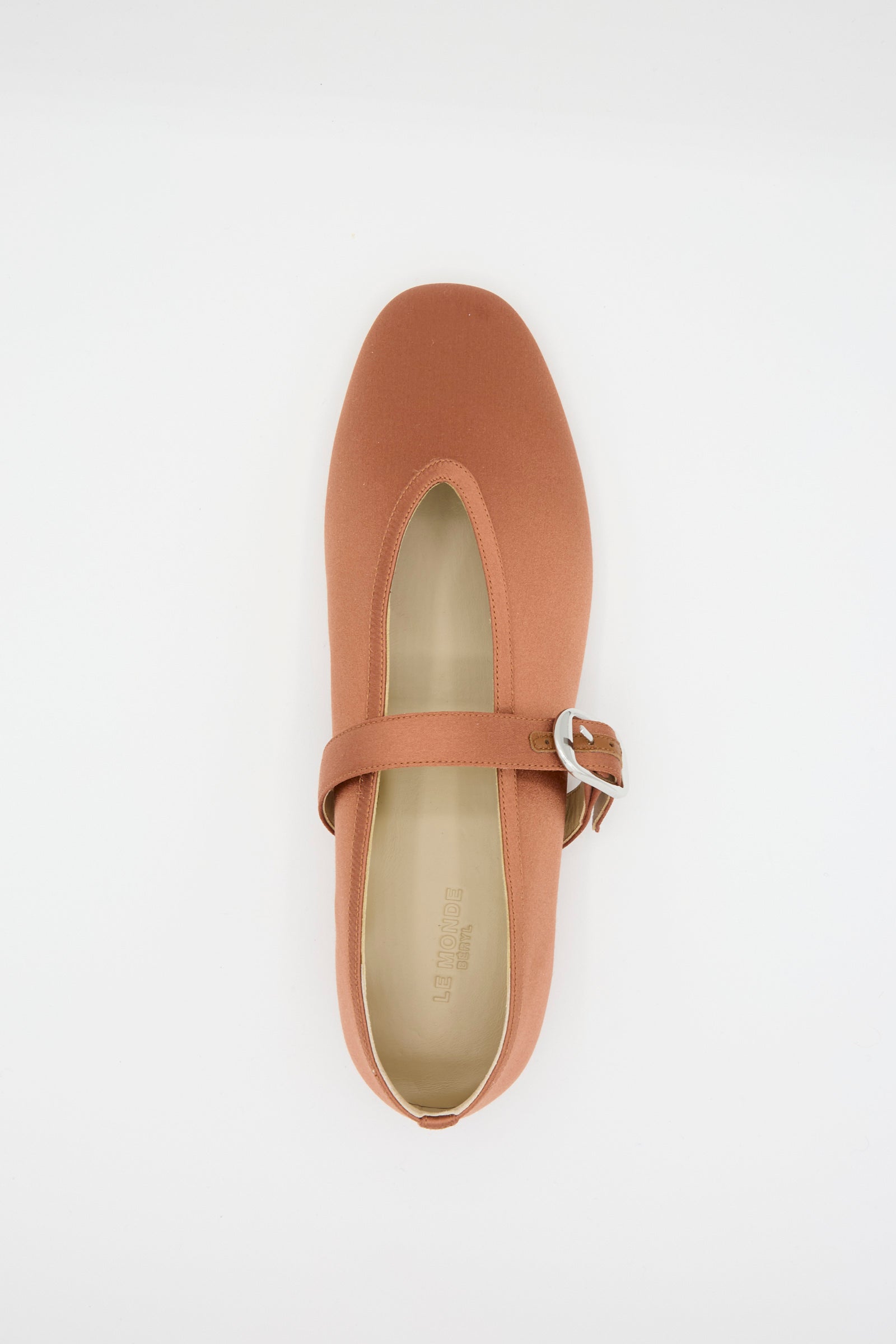 The Le Monde Beryl Stretch Satin Stella Slipper in Rust features a sleek strap and buckle across the top, viewed from above against a white background. 