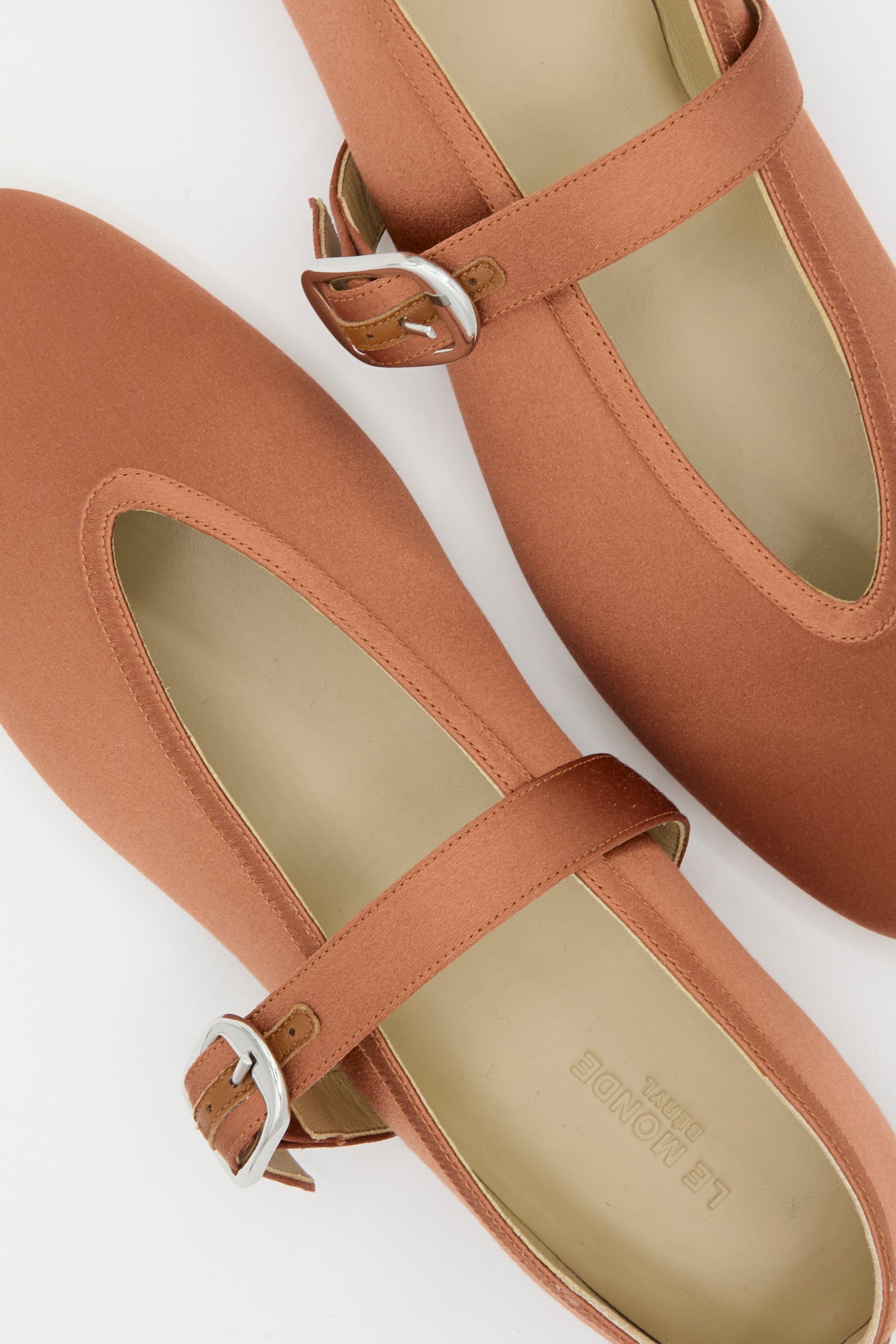 The Stretch Satin Stella Slipper in Rust by Le Monde Beryl, Italian-sized, has buckle straps and is shown side by side on a white background, close-up. 