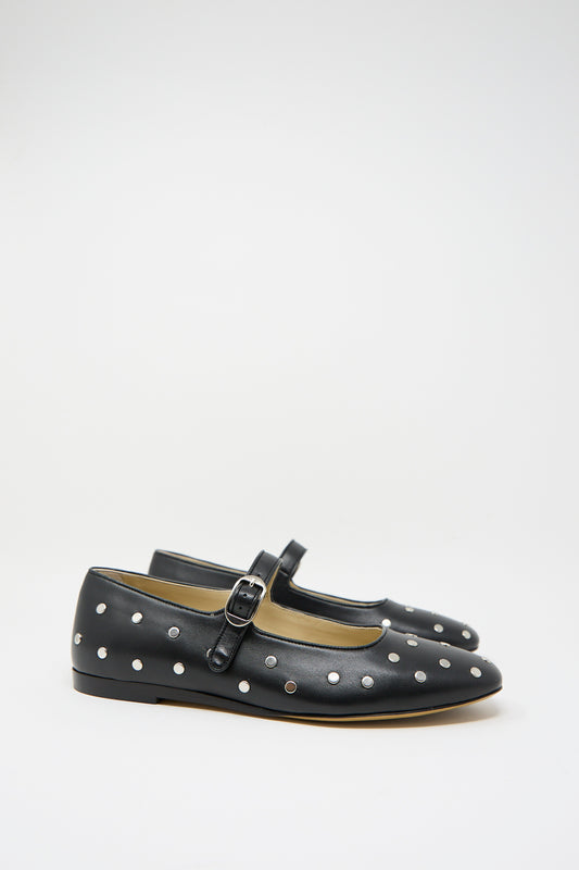 The Studded Leather Mary Jane in Black by Le Monde Beryl features black polka dots, a buckle strap, and silver metal studs on luxurious leather, showcased against a white background. 