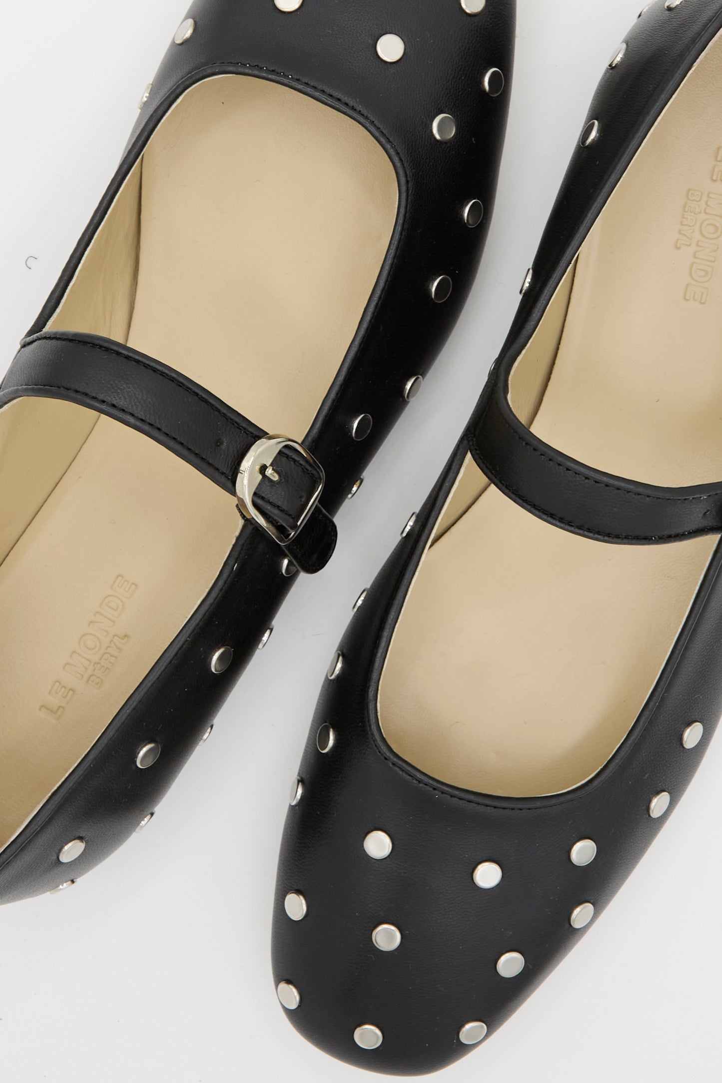 A pair of the Studded Leather Mary Jane in Black by Le Monde Beryl, adorned with silver metal studs and buckled straps, is  displayed from above on a white background.