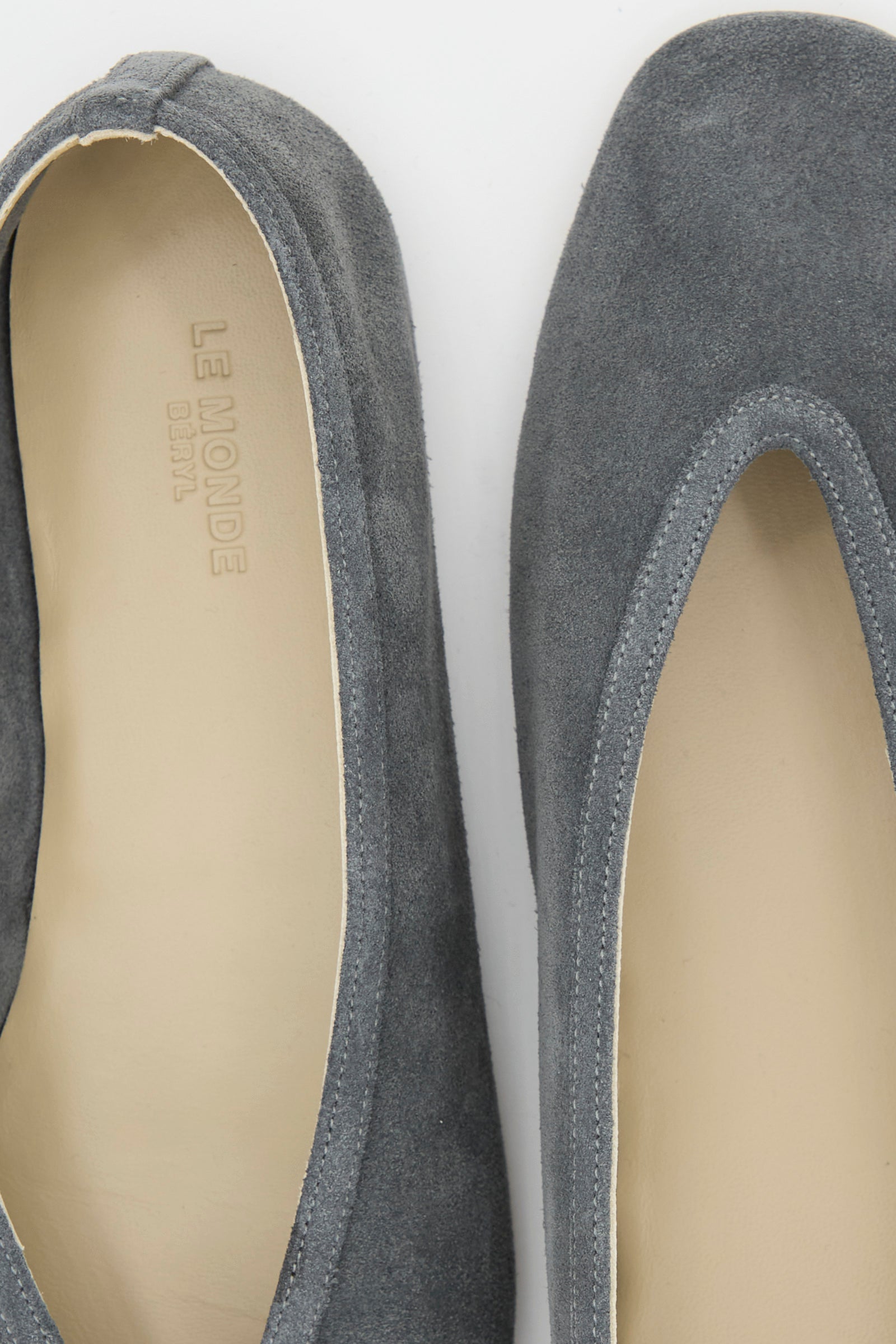 Close-up of a pair of  "Suede Luna Slipper" by Le Monde Beryl", anthracite suede slippers with a cream inner lining and calf leather insole.