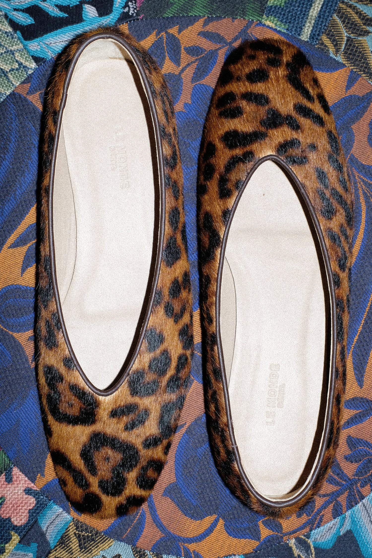 An image of the Le Monde Beryl Regency Slipper in Leopard on a colorful textile.
