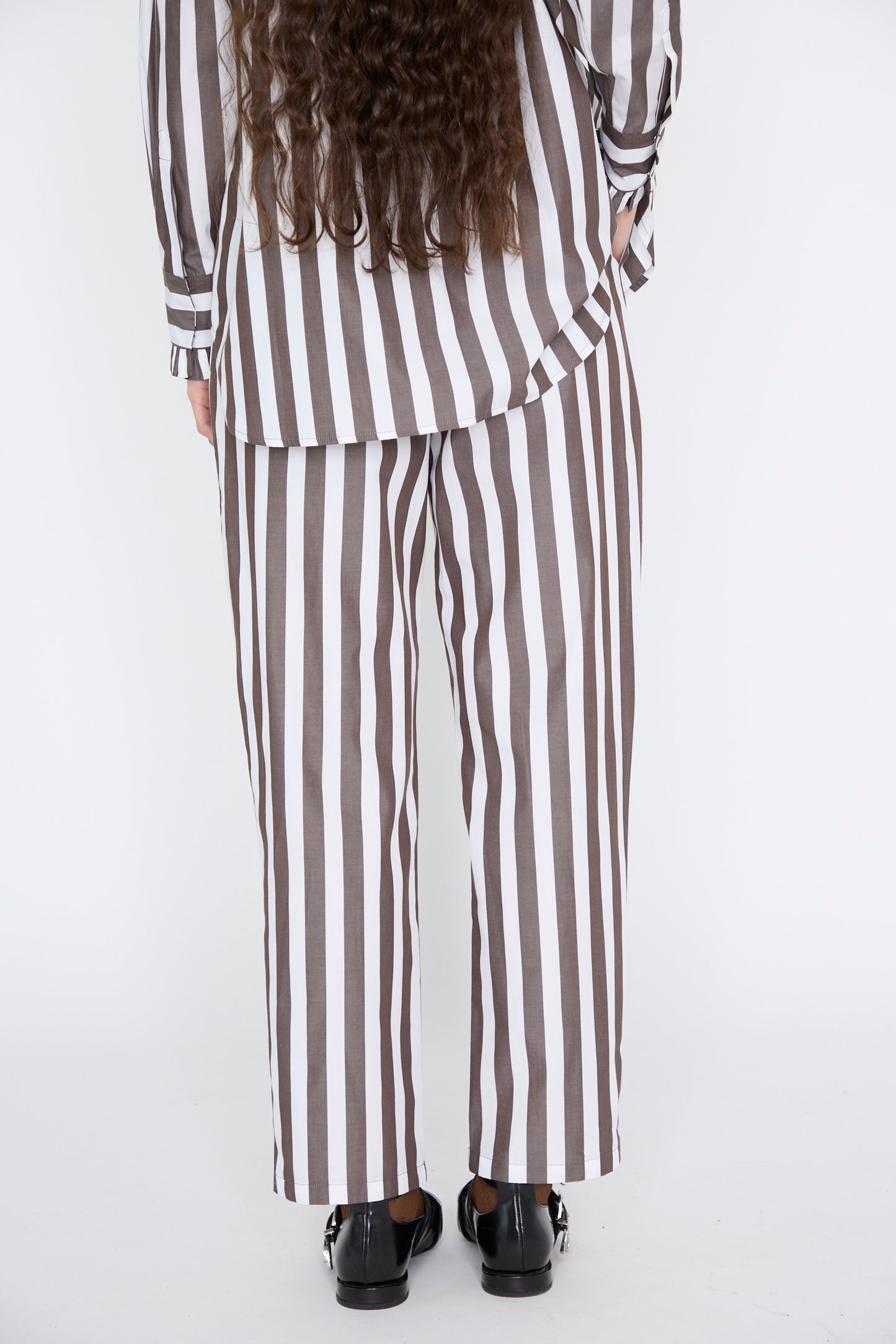 The Pantalon Nicolo in Marron by Les Prairies De Paris features vertical brown and white stripes crafted from organic cotton, offering a relaxed fit that perfectly blends style and comfort.