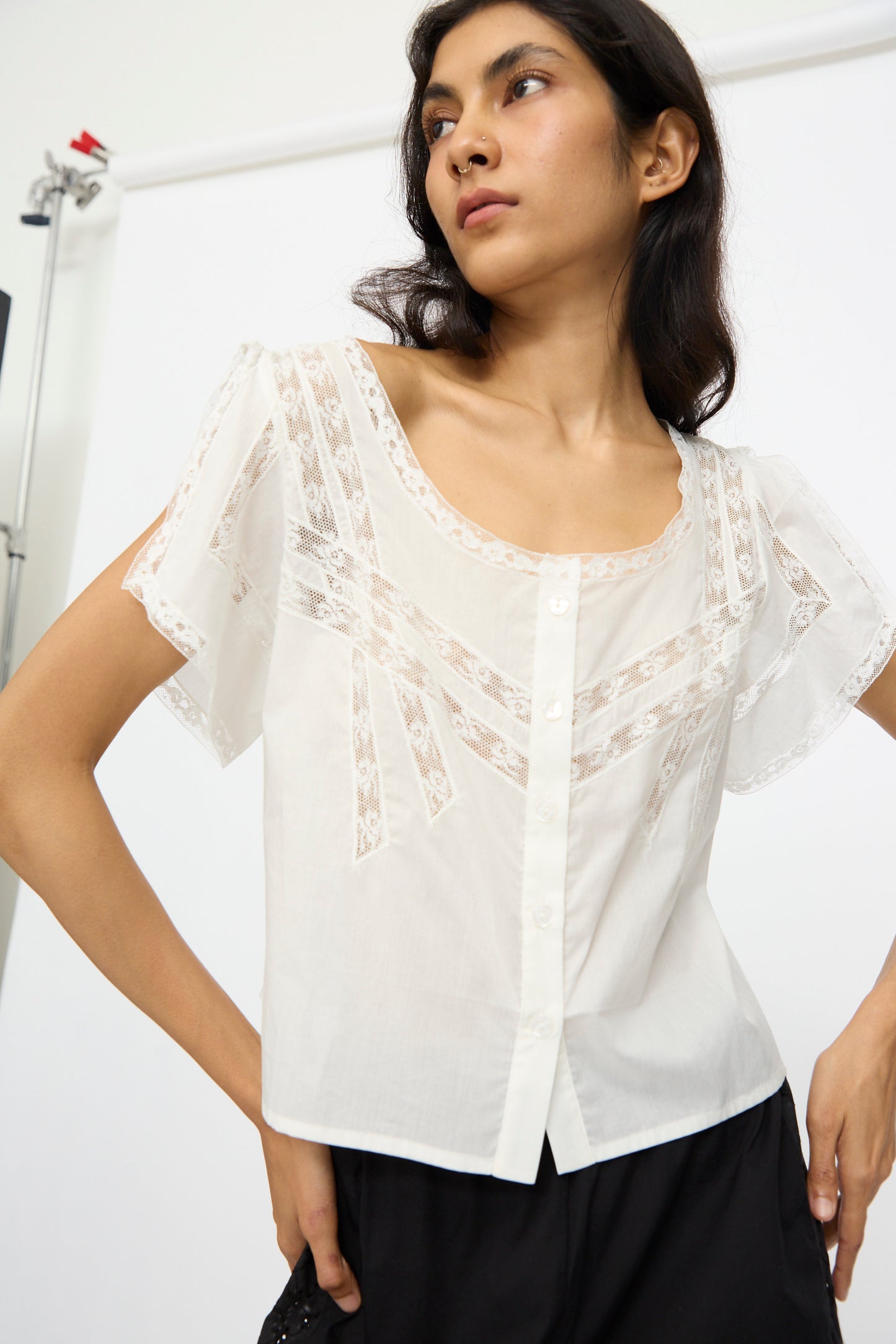 Wearing the Loretta Caponi Angela Top in Sunrise and black pants, a person stands against a plain white background, looking to the side.