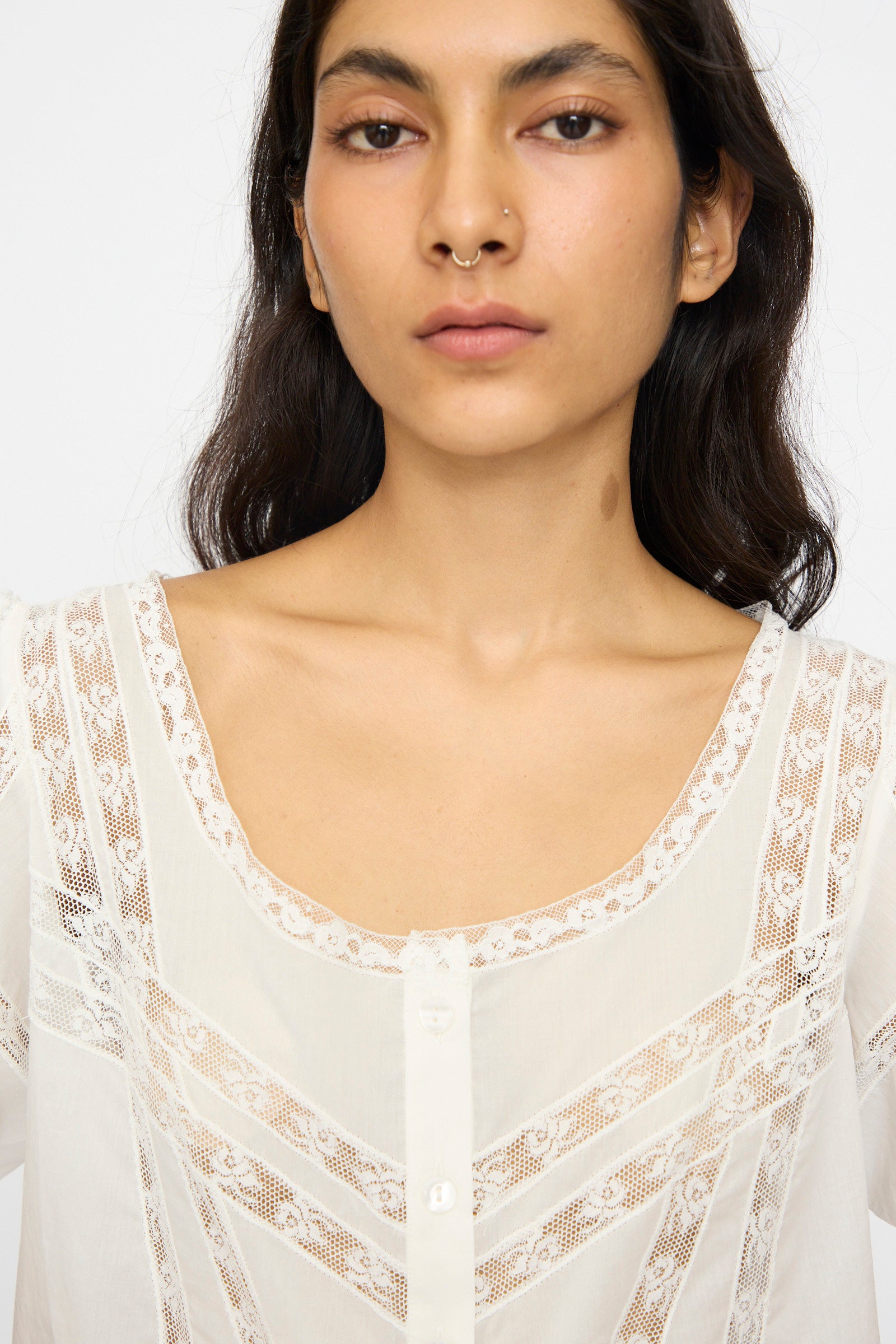 A person with long dark hair and a nose ring wears the Loretta Caponi Angela Top in Sunrise, facing the camera against a plain background.