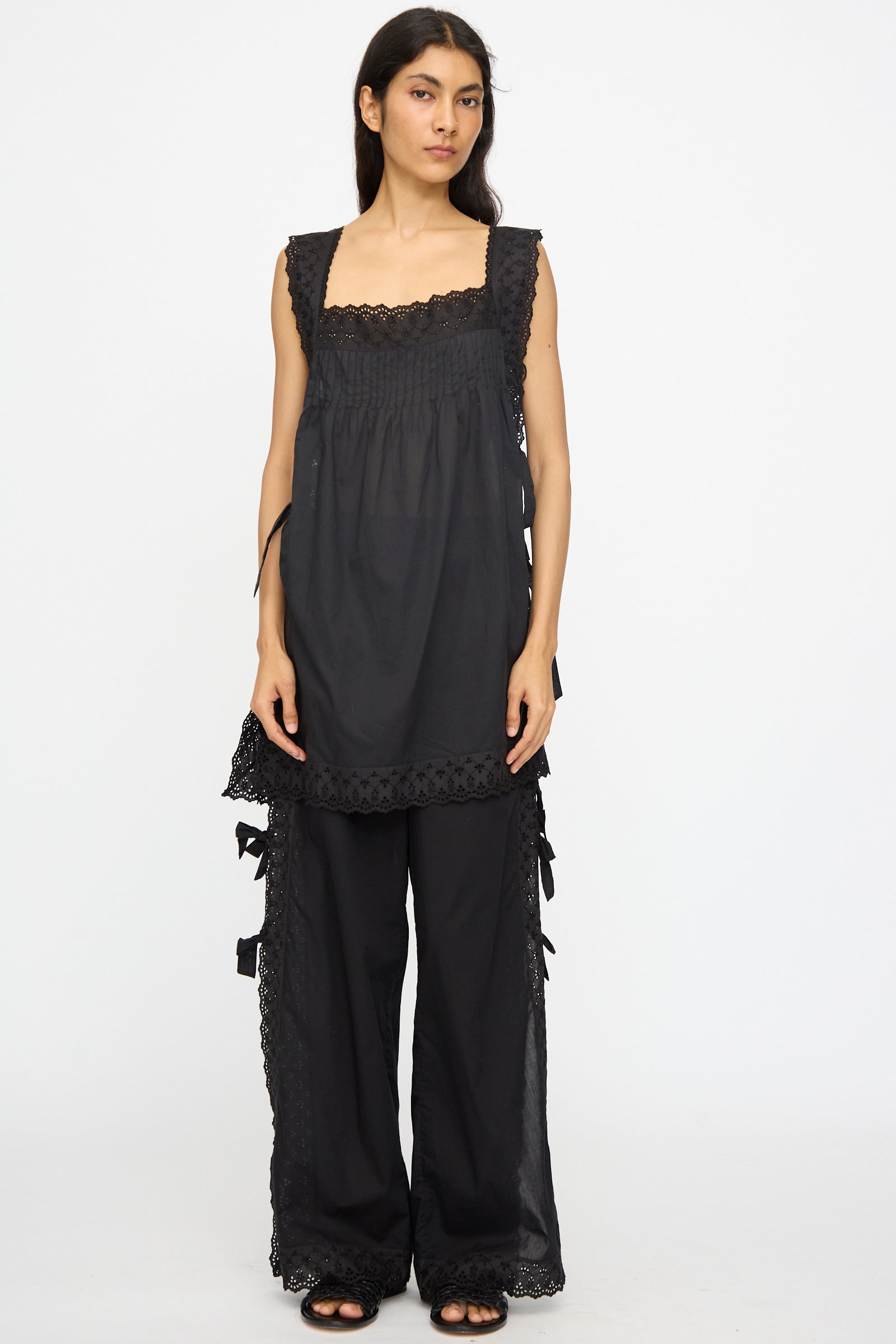 A woman faces forward wearing Loretta Caponi's Clarissa Trousers in Nero with a sleeveless black tunic featuring lace trim, set against a plain white background.