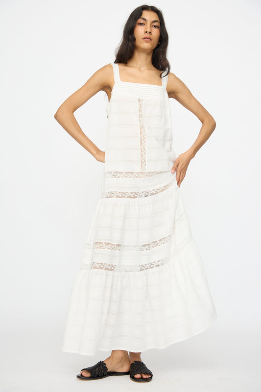 A woman stands against a white background wearing the Loretta Caponi Populonia Dress in Off White and black slide sandals.