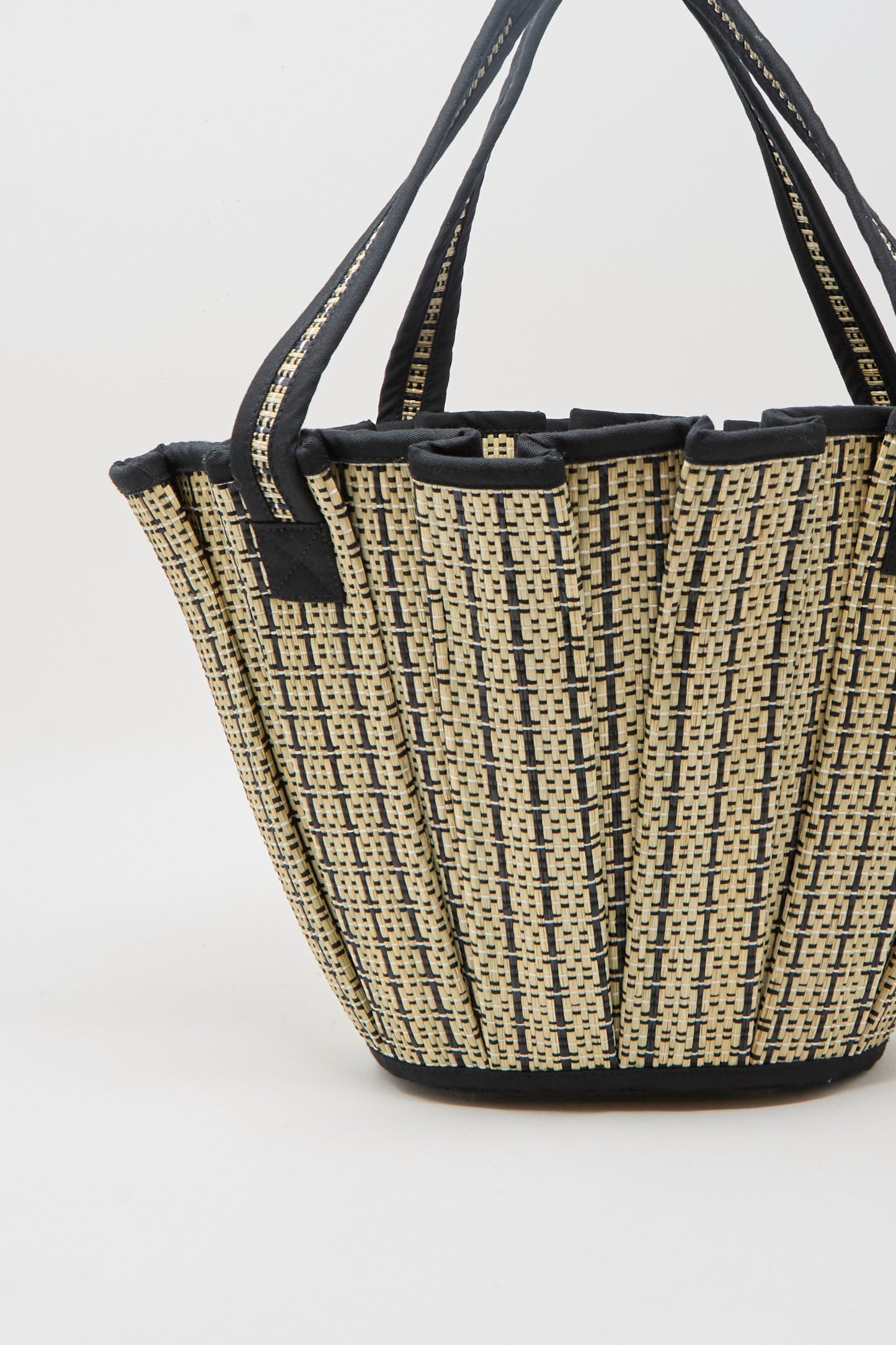 The Mini Tropez Tote in Lovers Point by Lorna Murray is a basket-style woven bag featuring black and beige checkered patterns, black trim, and two handles, crafted from natural grass fibers and shown on a plain white background.
