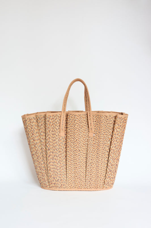 The Lorna Murray Tropez Tote in Dawn, made from natural grass fibre with two sturdy handles, is displayed against a plain white background.