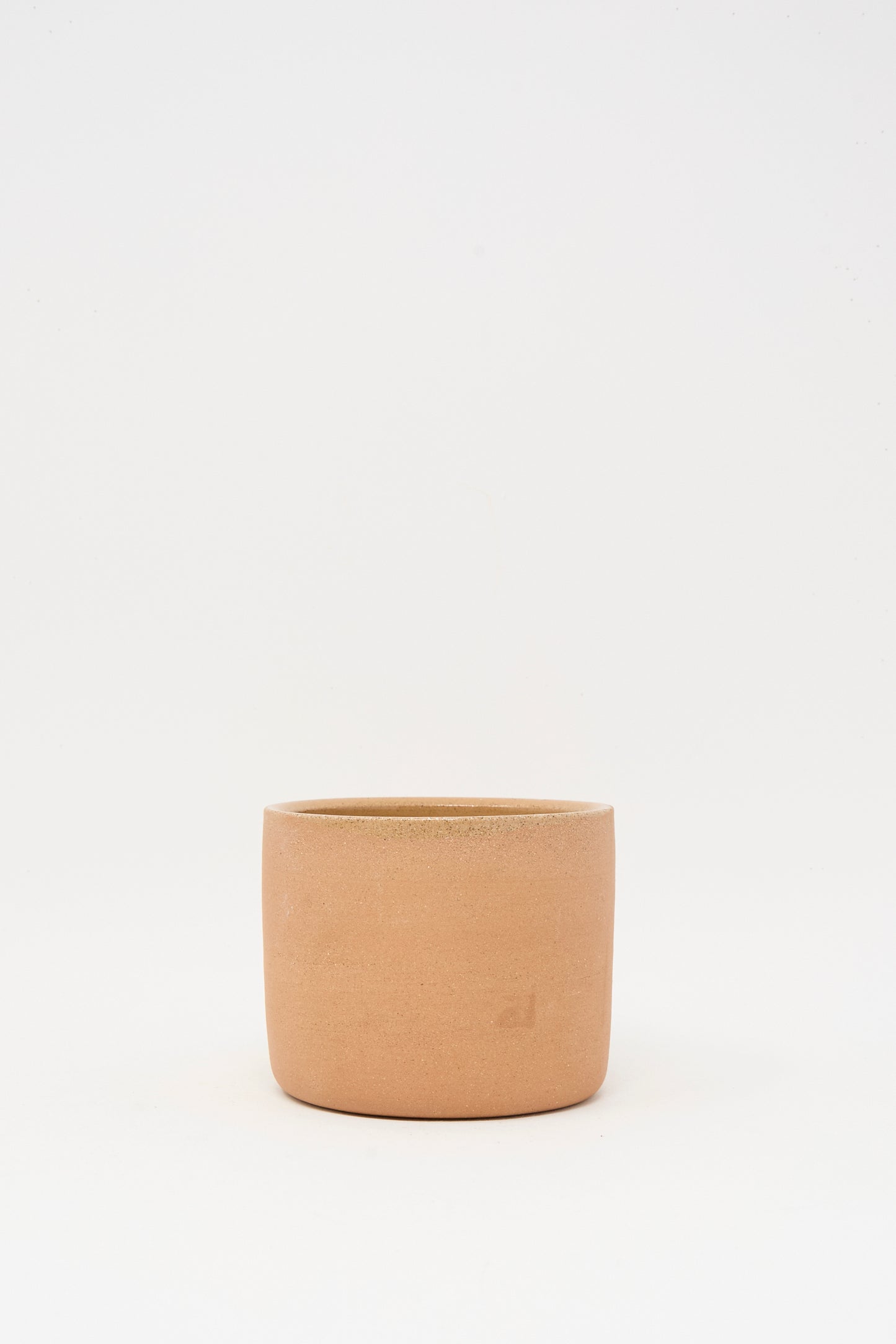 The Bow Knot Mug in Adobe by Lost Quarry, with its plain, cylindrical form and earthy terracotta hue, sits centered on a white background, echoing the natural charm of handmade ceramics.