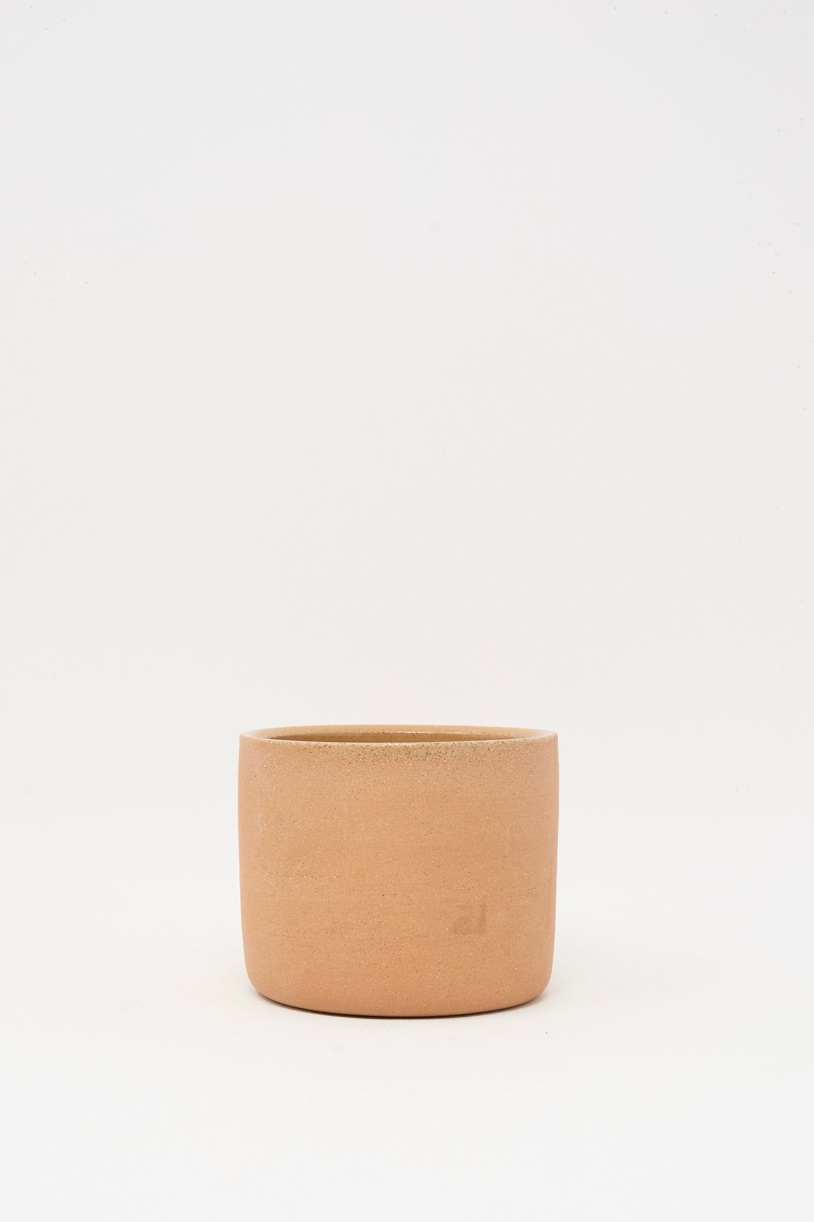 The Bow Knot Mug in Adobe by Lost Quarry, with its plain, cylindrical form and earthy terracotta hue, sits centered on a white background, echoing the natural charm of handmade ceramics.