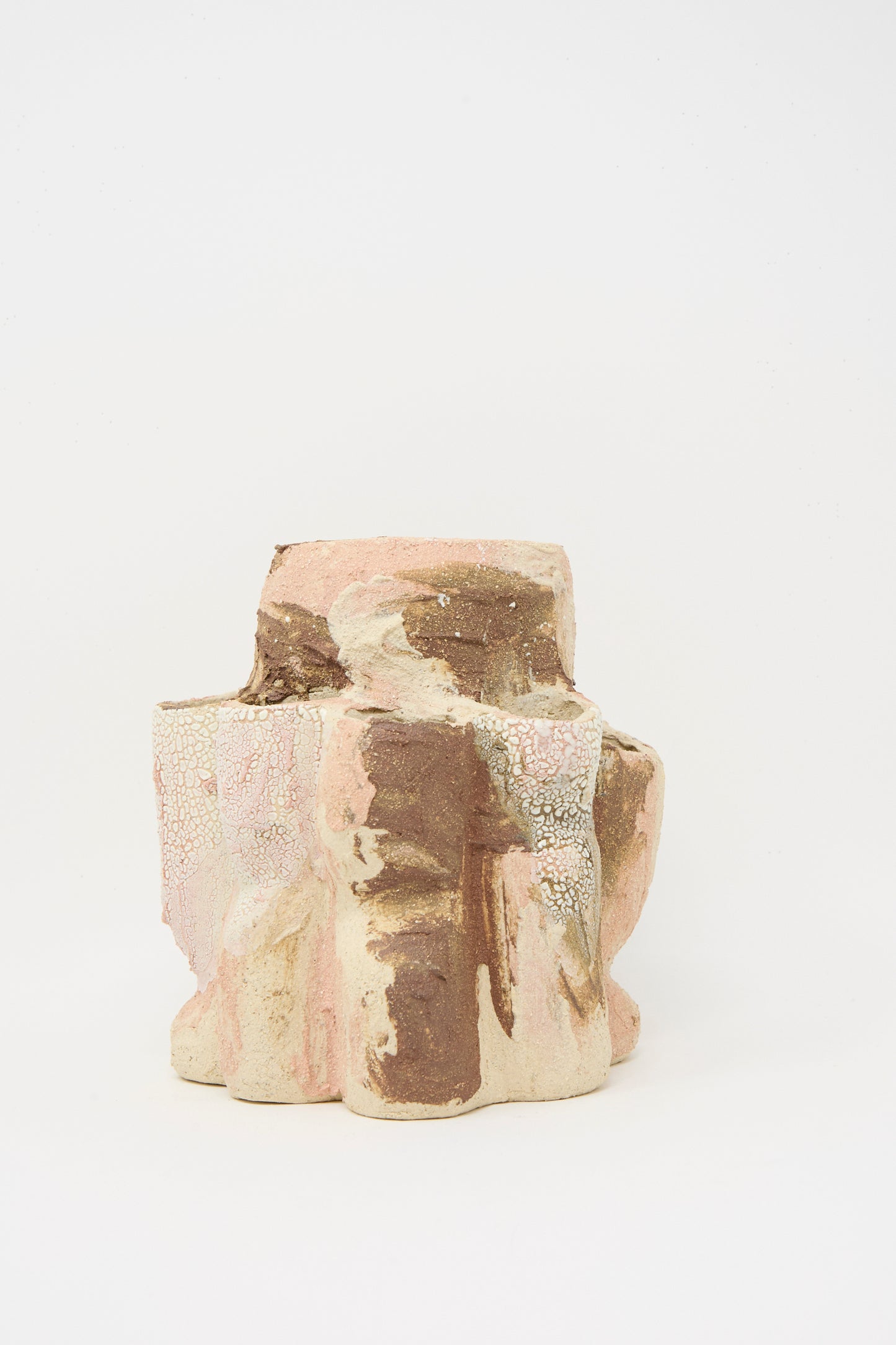 The Hand Built Clay Tulipiere Vessel by Lost Quarry, featuring earthy brown, beige, and light pink tones with a textured sculptural design, is displayed against a plain white background.