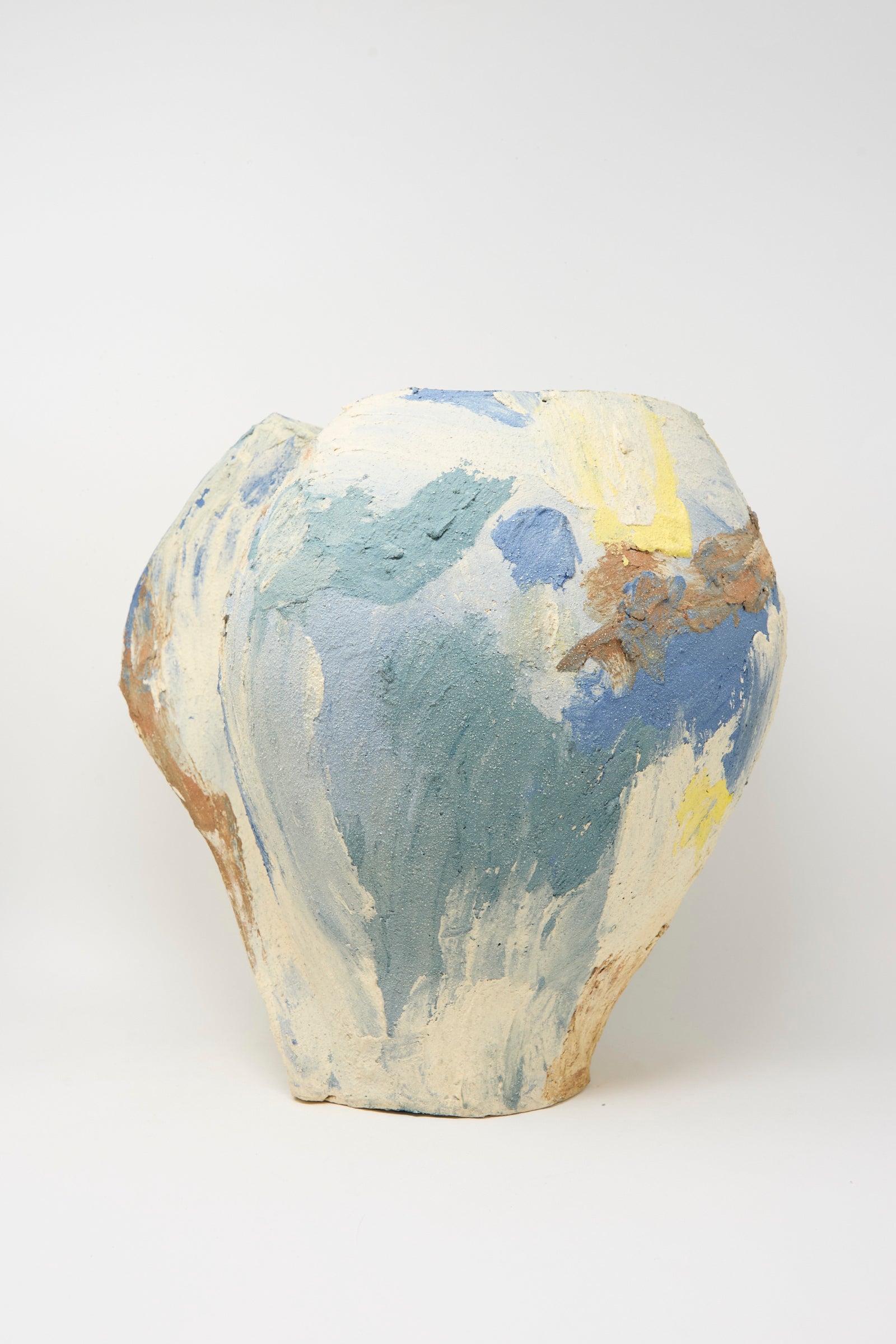 The Hand Built Cloudy Day Vessel by Lost Quarry is a uniquely shaped handmade ceramic piece with a rough finish, showcasing abstract blue, yellow, and beige patterns on a neutral base.