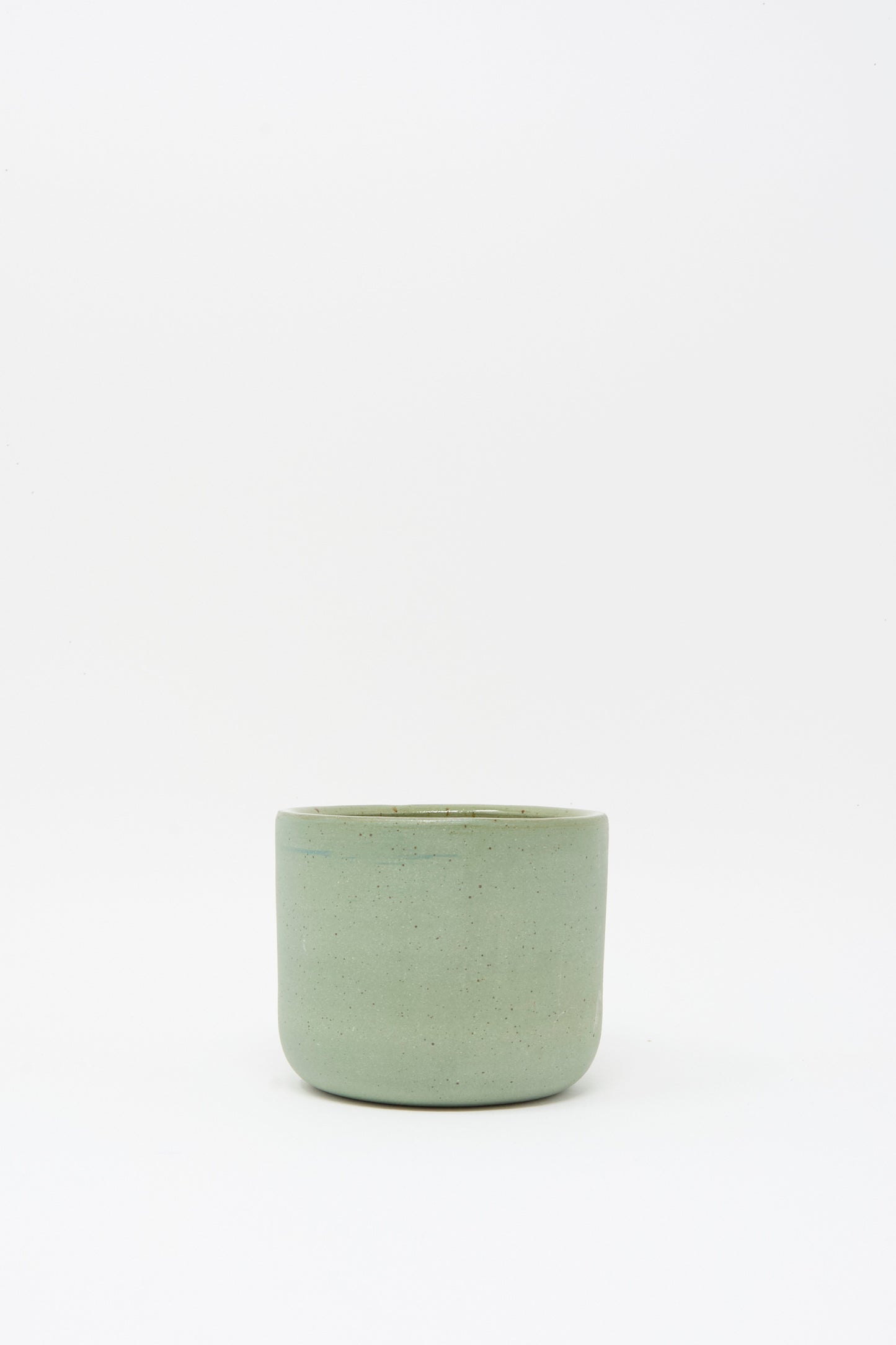 The Hand Built Knot Mug in Sage I by Lost Quarry, a small light green handmade ceramic mug with an oversized handle, is centered against a plain white background.