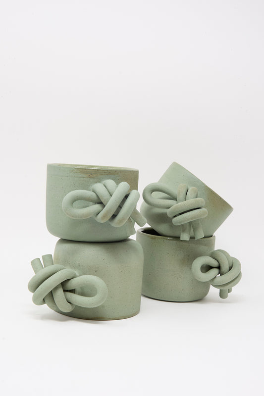 Four Hand Built Knot Mugs in Sage I by Lost Quarry, featuring twisted oversized handles, are stacked against a plain white background.