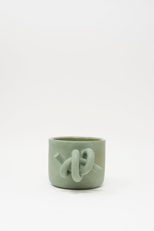 The Hand Built Knot Mug in Sage II by Lost Quarry is a light green ceramic mug with a sculpted knot design and smooth sage glaze, shown against a plain white background.