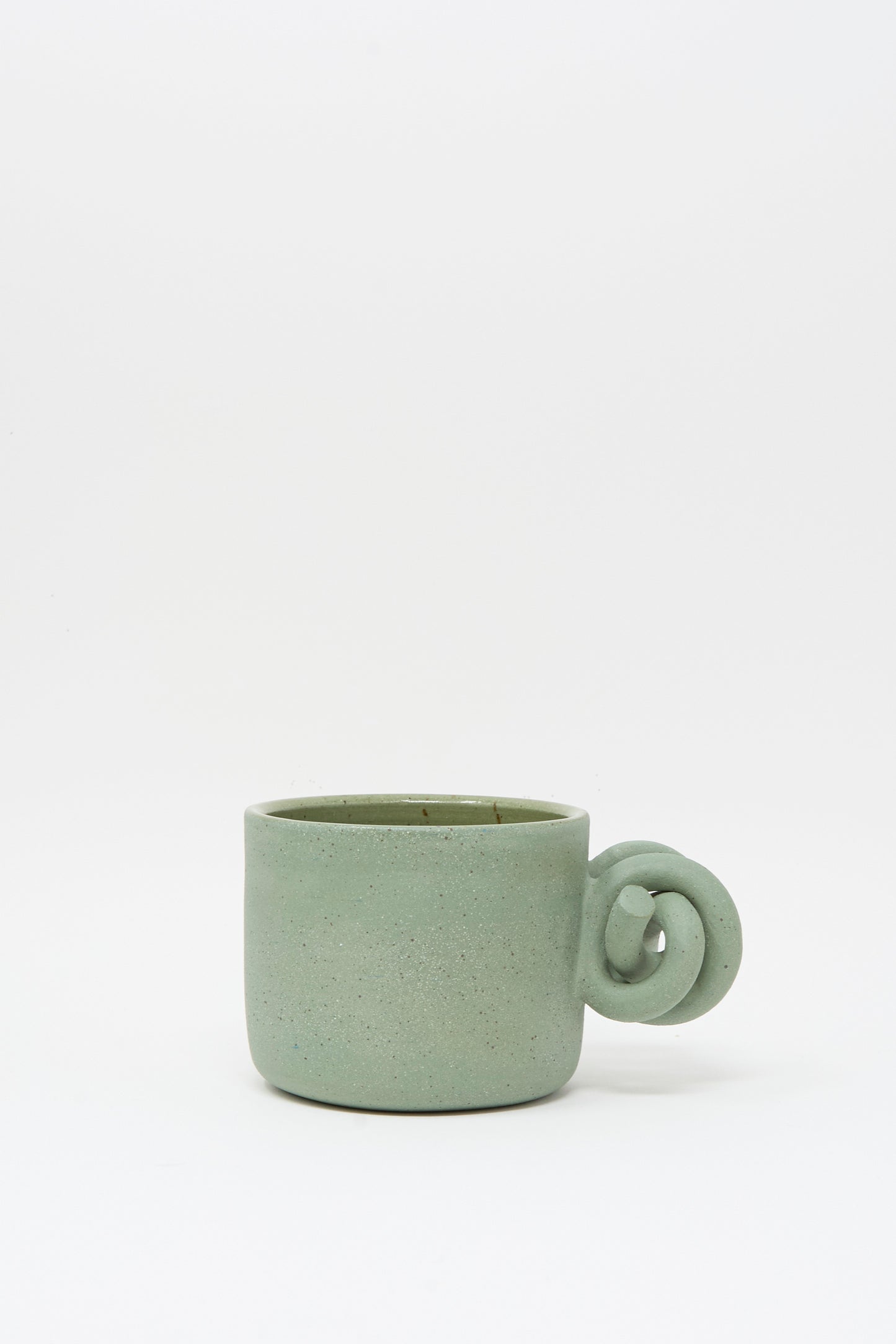 The Hand Built Knot Mug in Sage II by Lost Quarry features a handmade green ceramic design with a unique knot-shaped handle and a smooth sage glaze, displayed on a plain white background.