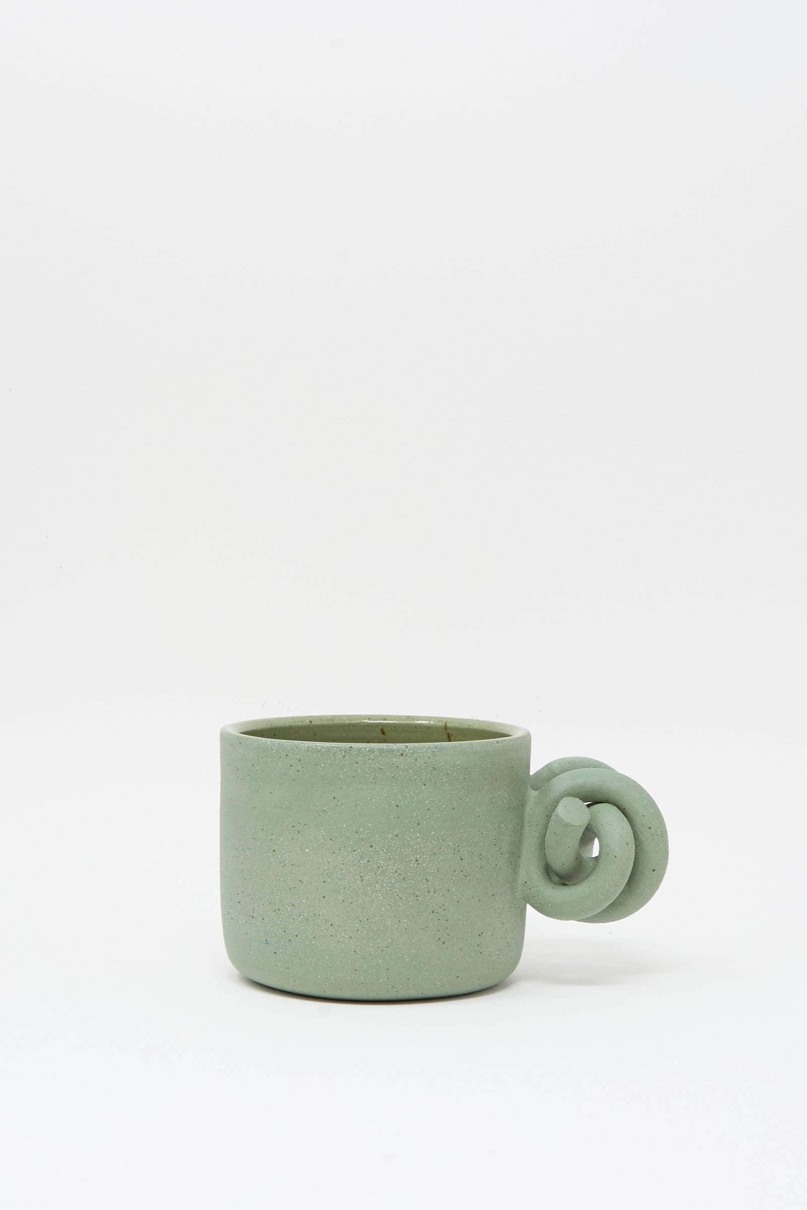 The Hand Built Knot Mug in Sage II by Lost Quarry features a handmade green ceramic design with a unique knot-shaped handle and a smooth sage glaze, displayed on a plain white background.