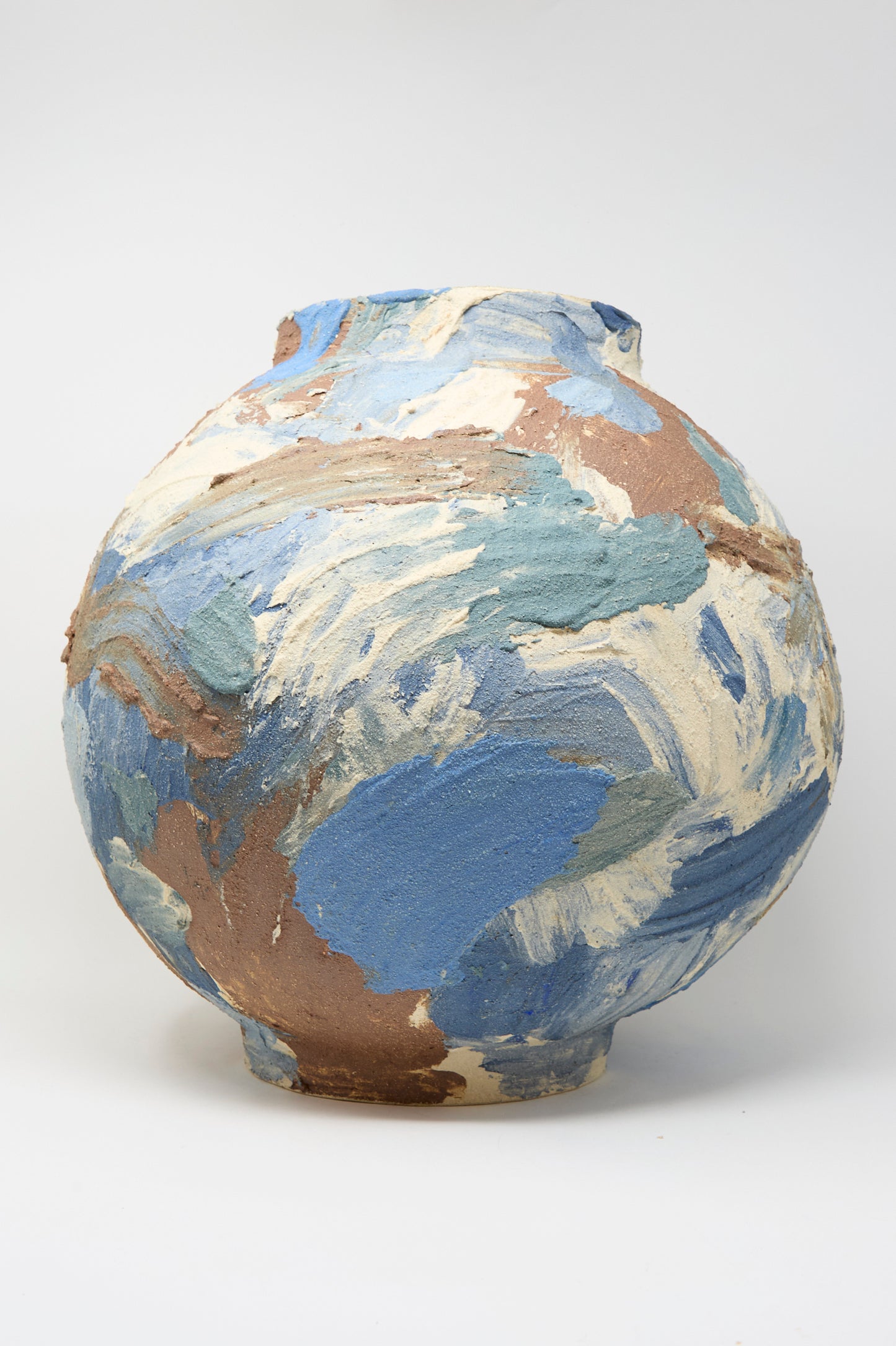 The Hand Built Waves Vessel by Lost Quarry is a handmade round ceramic piece, featuring a rough texture and abstract swirls of blue, cream, and brown on white—crafted in Brooklyn.