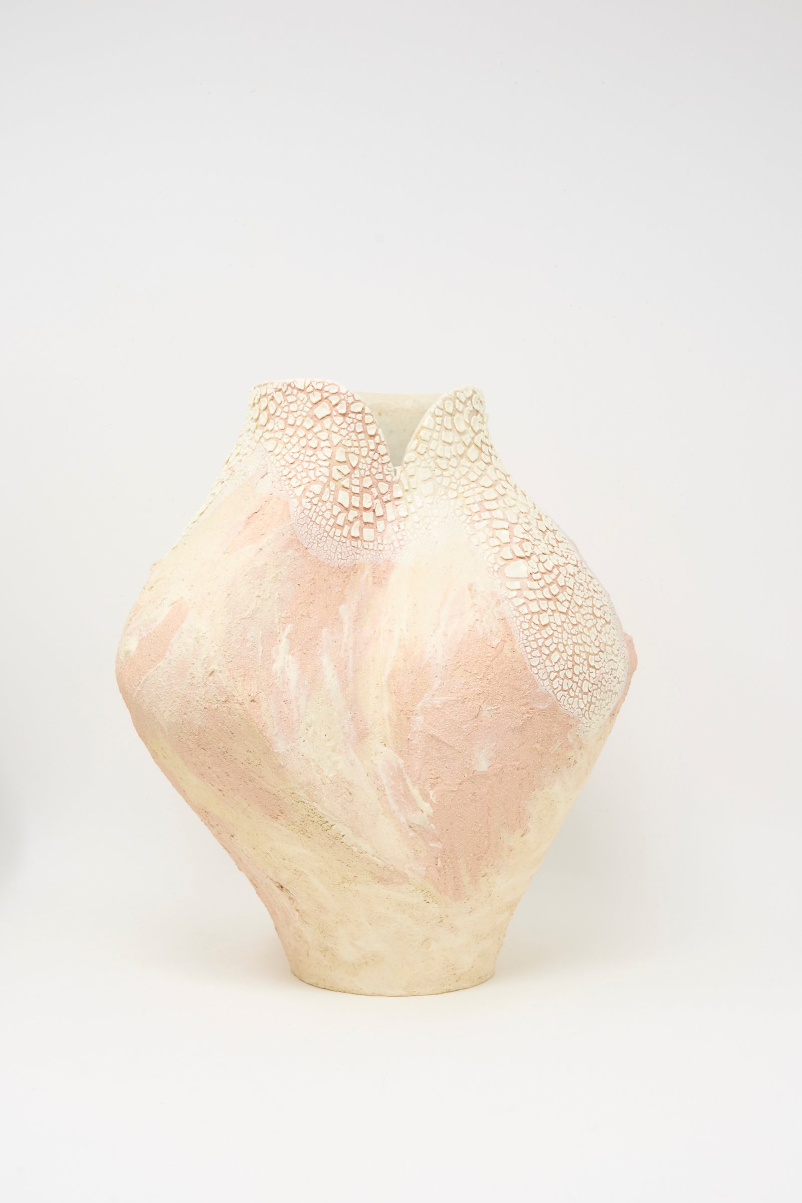 The Lost Quarry Hand Built Textured Vessel in Pale Pink features an asymmetrical ceramic form with a cracked white glaze near the rim and a smooth pale pink and cream body, displayed on a plain white background.