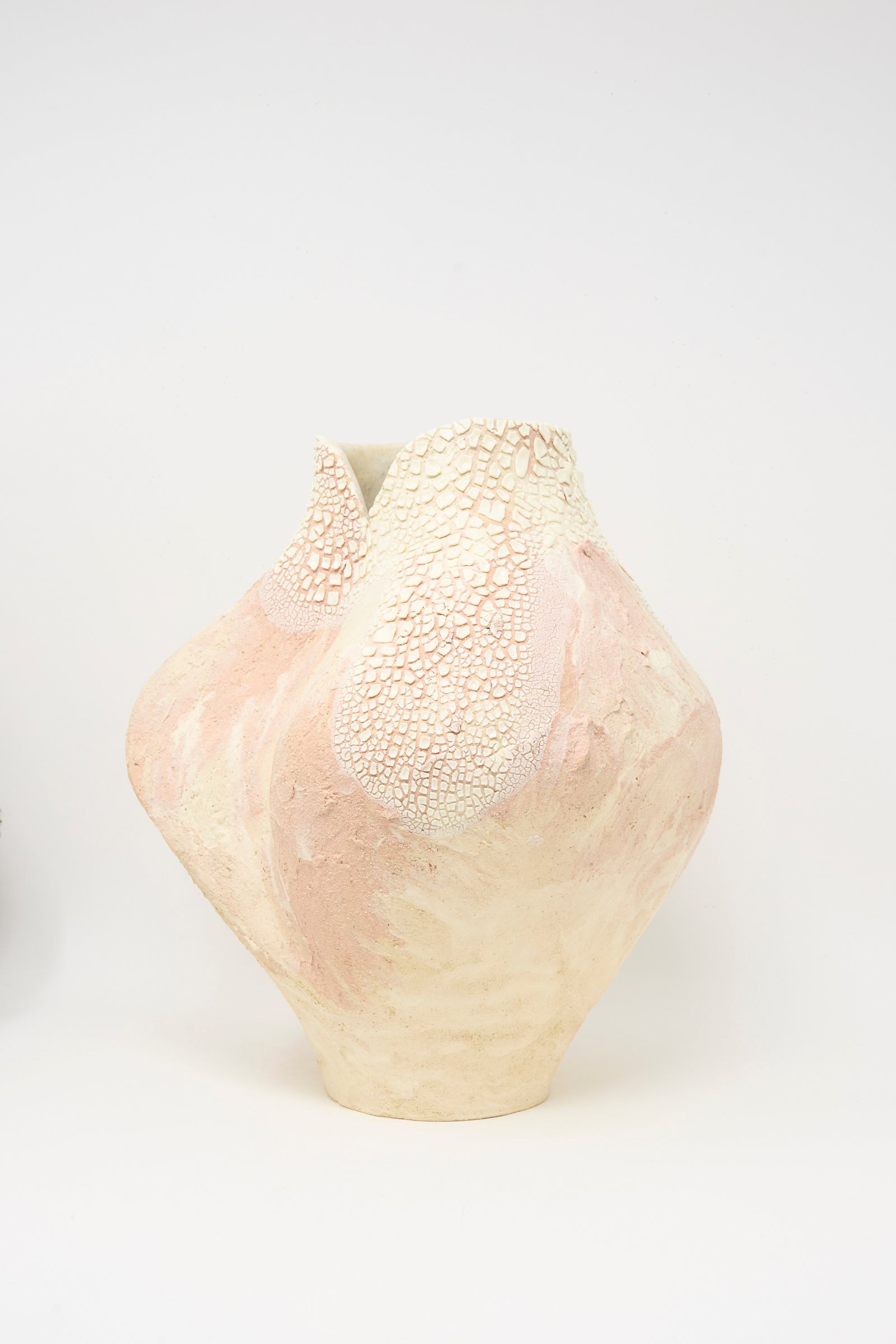 The Lost Quarry Hand Built Textured Vessel in Pale Pink features a cream and pale pink ceramic design with a cracked pattern near the rim, displayed against a plain white background.