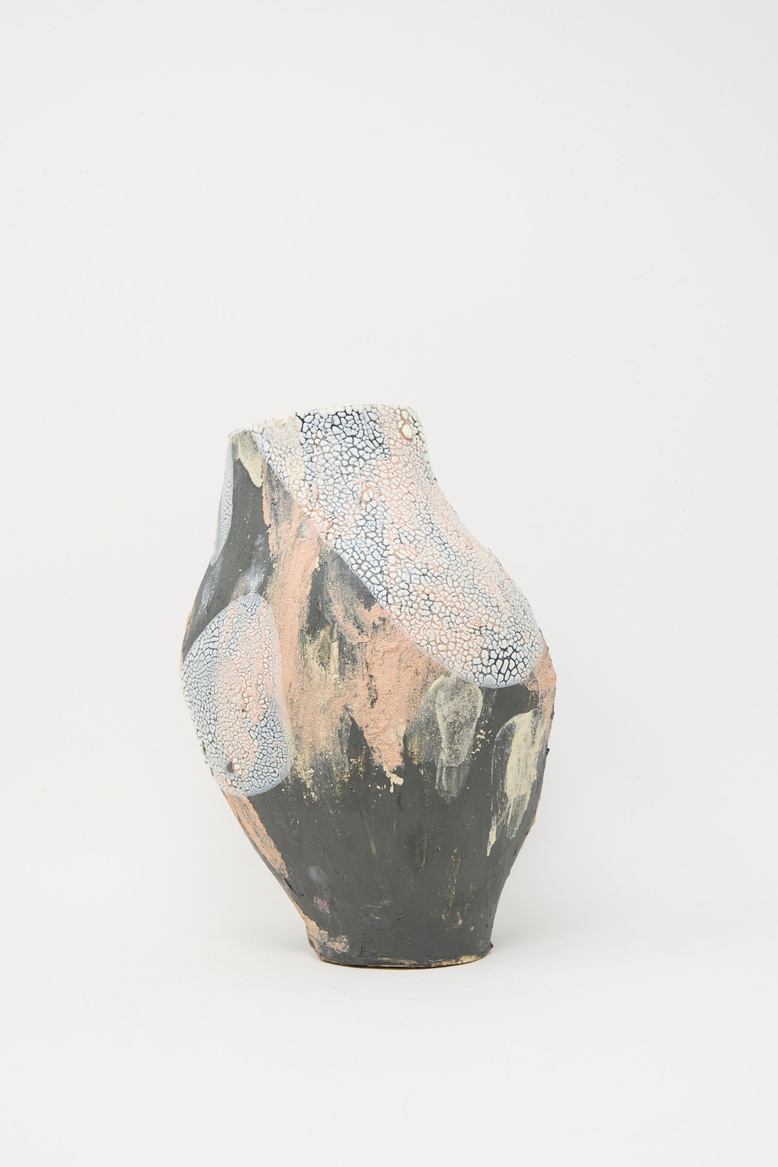 The Lost Quarry Medium Hand Built Textured Vessel in Black Pink Multi is an asymmetrical ceramic piece with a rough surface, showcasing black, pink, and white hues on a plain white background.
