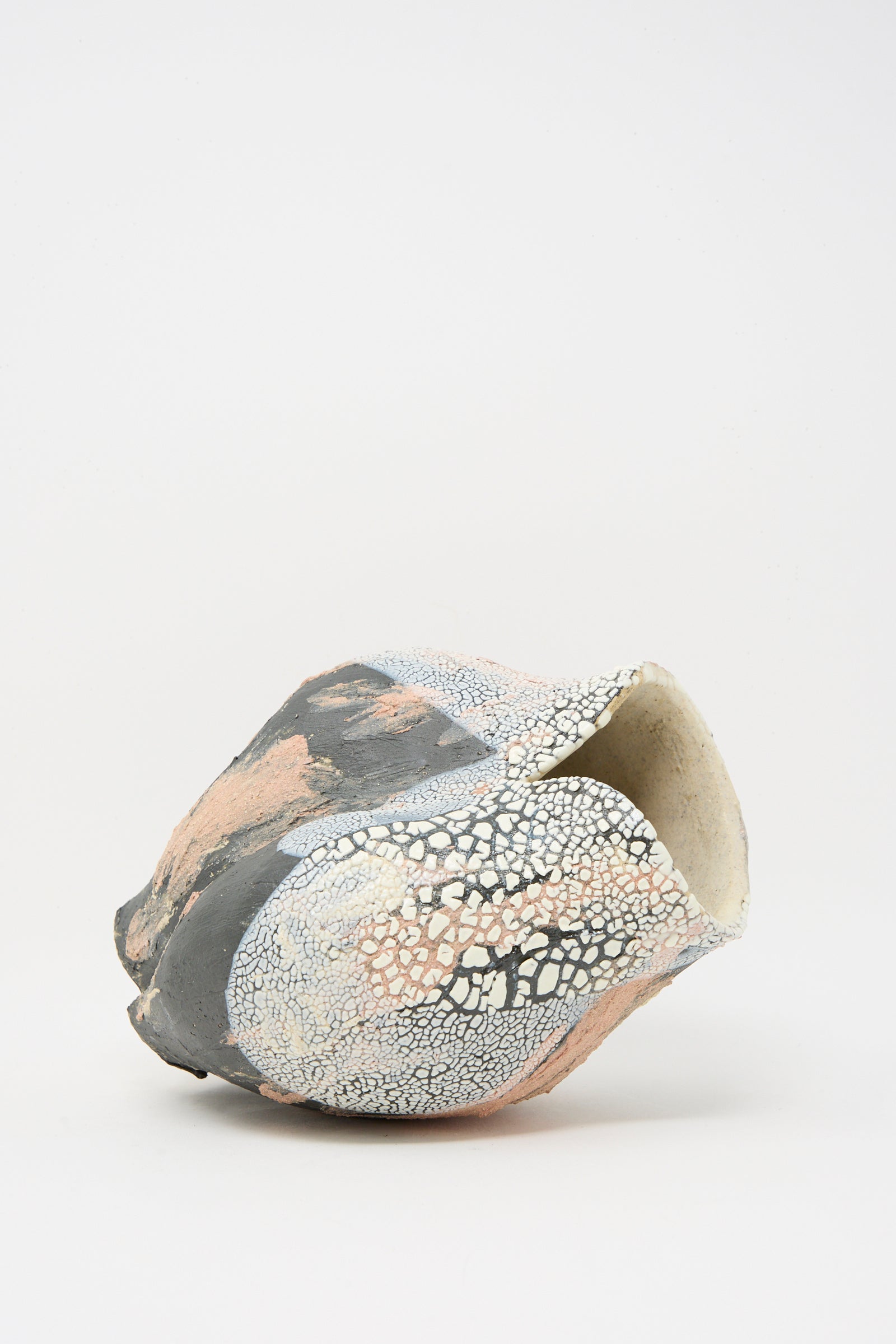 The Lost Quarry Medium Hand Built Textured Vessel in Black Pink Multi features an irregular ceramic form, sculptural clay details, and a cracked, textured surface in black, white, and pink against a plain white background.