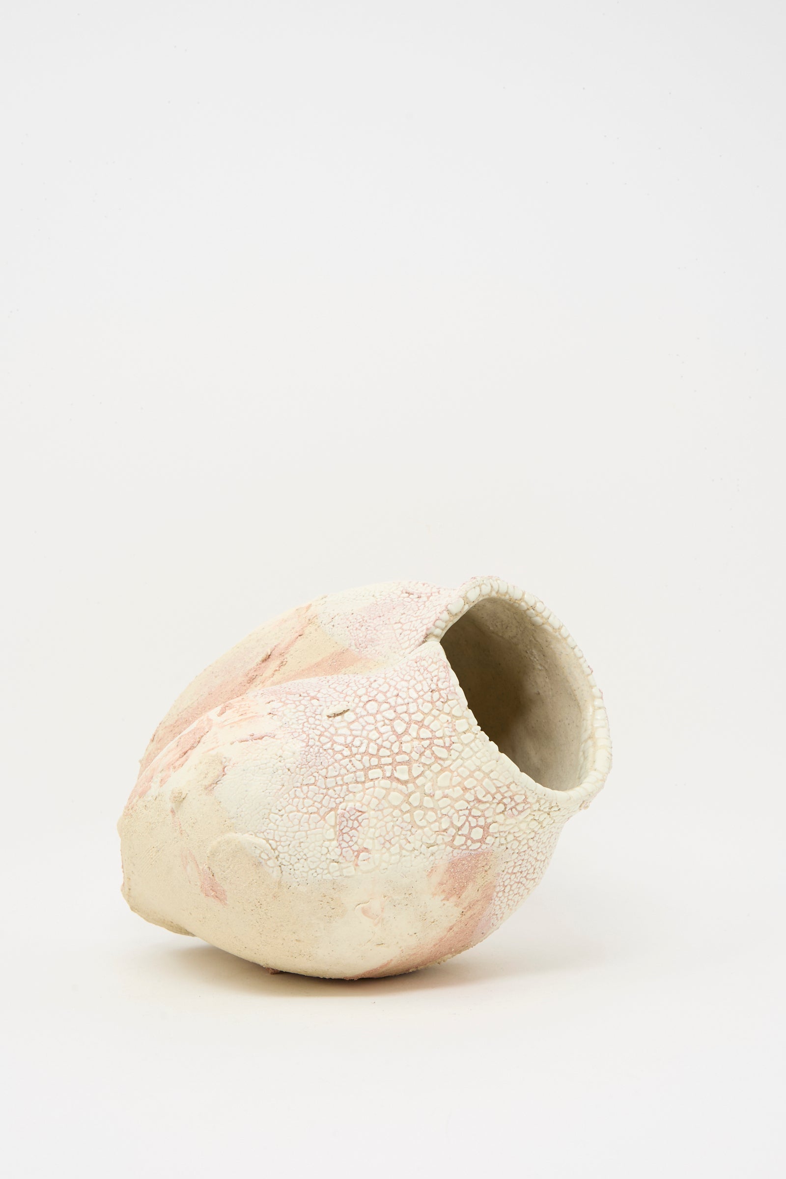 Lost Quarry’s Medium Hand Built Textured Vessel in Pale Pink features an irregular shape and cracked, textured surface in pale pink and off-white tones, displayed against a plain white background.