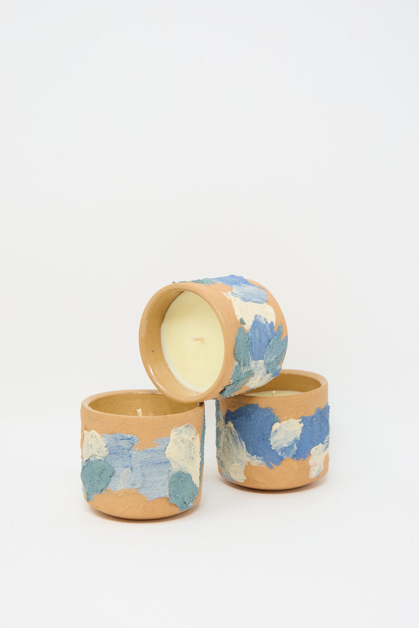Three Lost Quarry Neroli Candles in hand-built blue and white terracotta vessels are arranged on a plain white background.