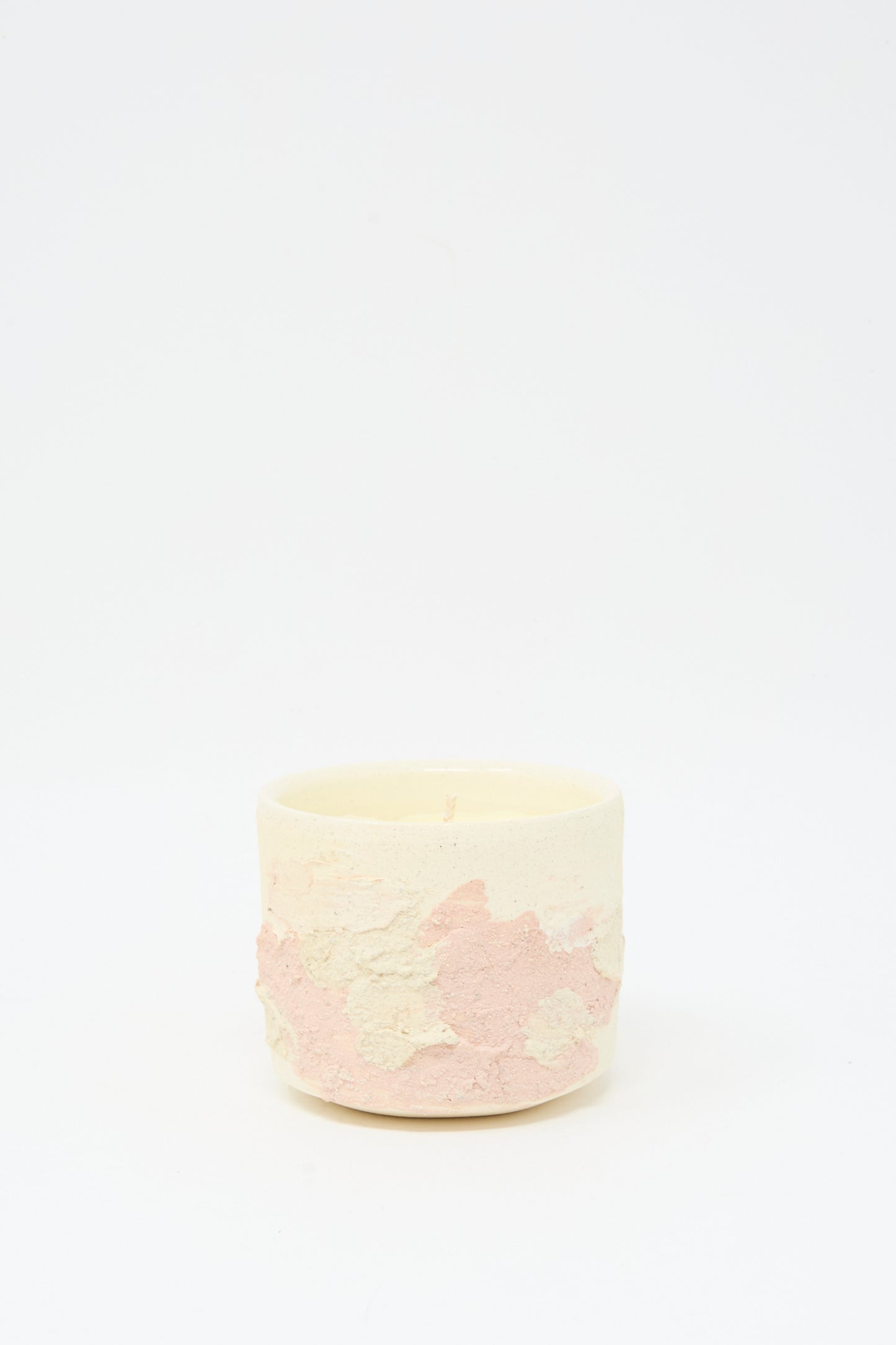 The Neroli Candle in Pink Multi by Lost Quarry is a small, round scented candle set in a hand-built ceramic vessel with pale pink and cream hues, displayed against a plain white background.