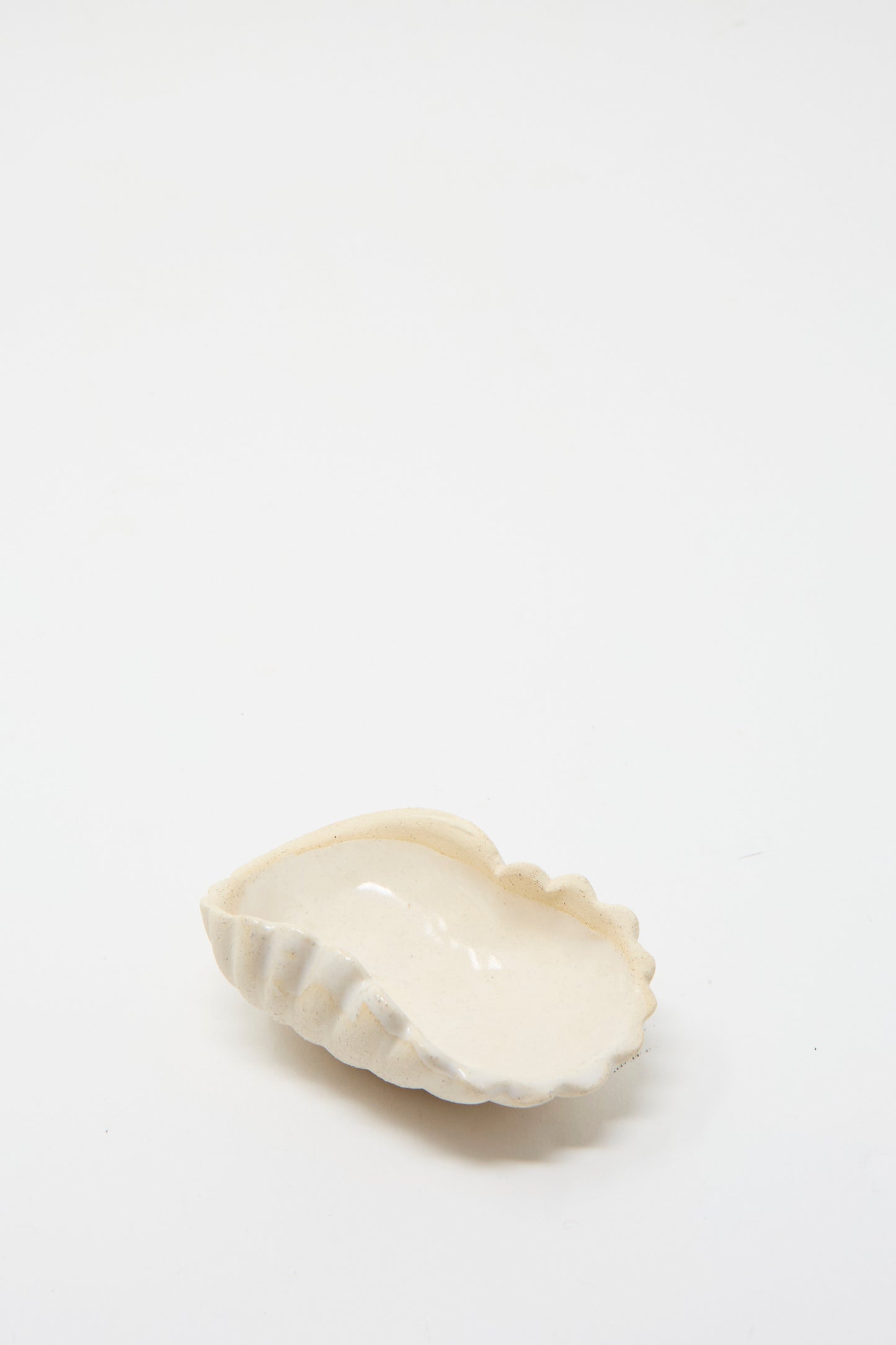 The Small Ceramic Shell Dish in Cream by Lost Quarry is set against a plain white background, facing up. 