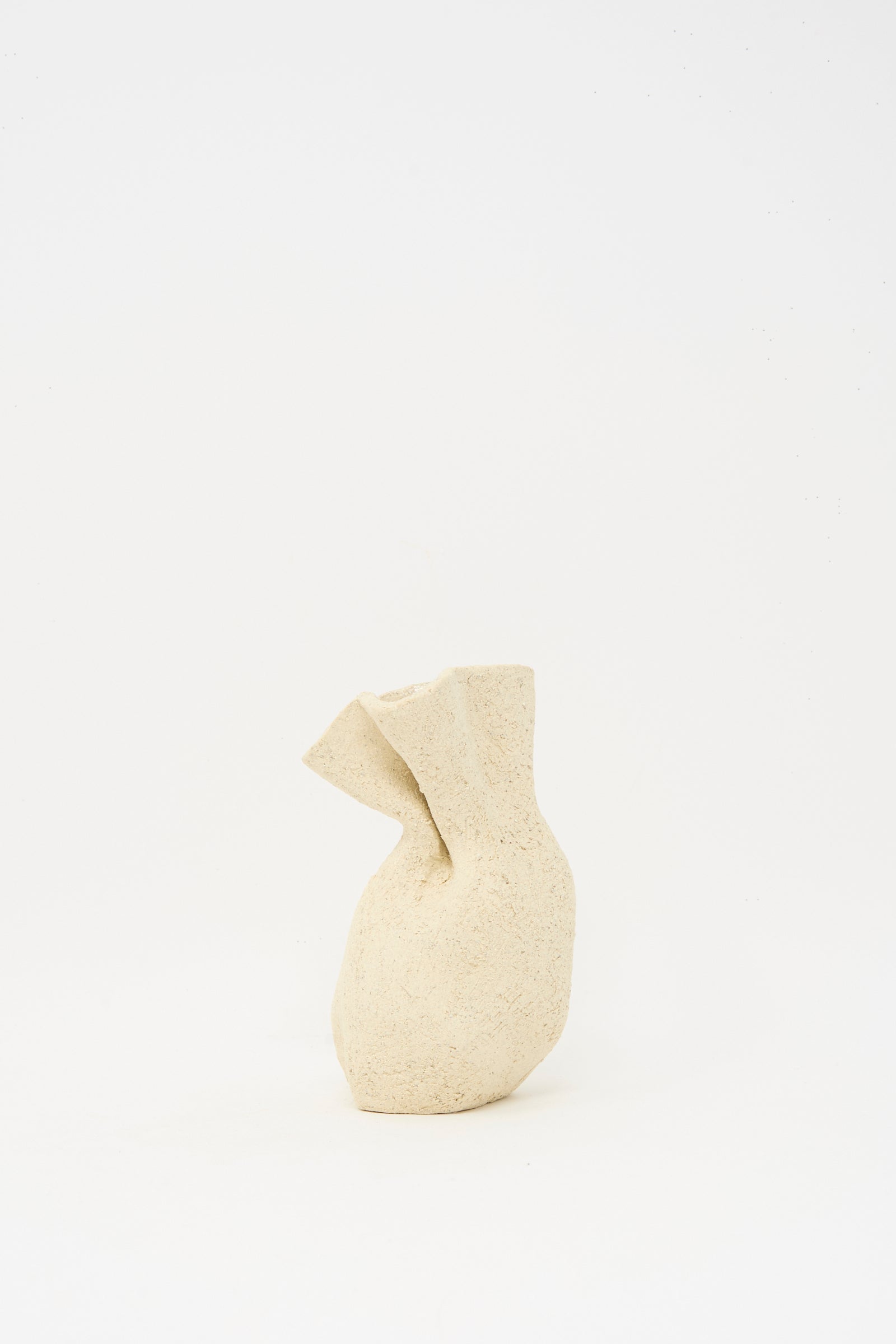 The Lost Quarry Textured Clay Folded Vessel I is a beige, irregularly shaped ceramic vase with a rough texture, made from white sculpture clay and displayed against a plain white background.
