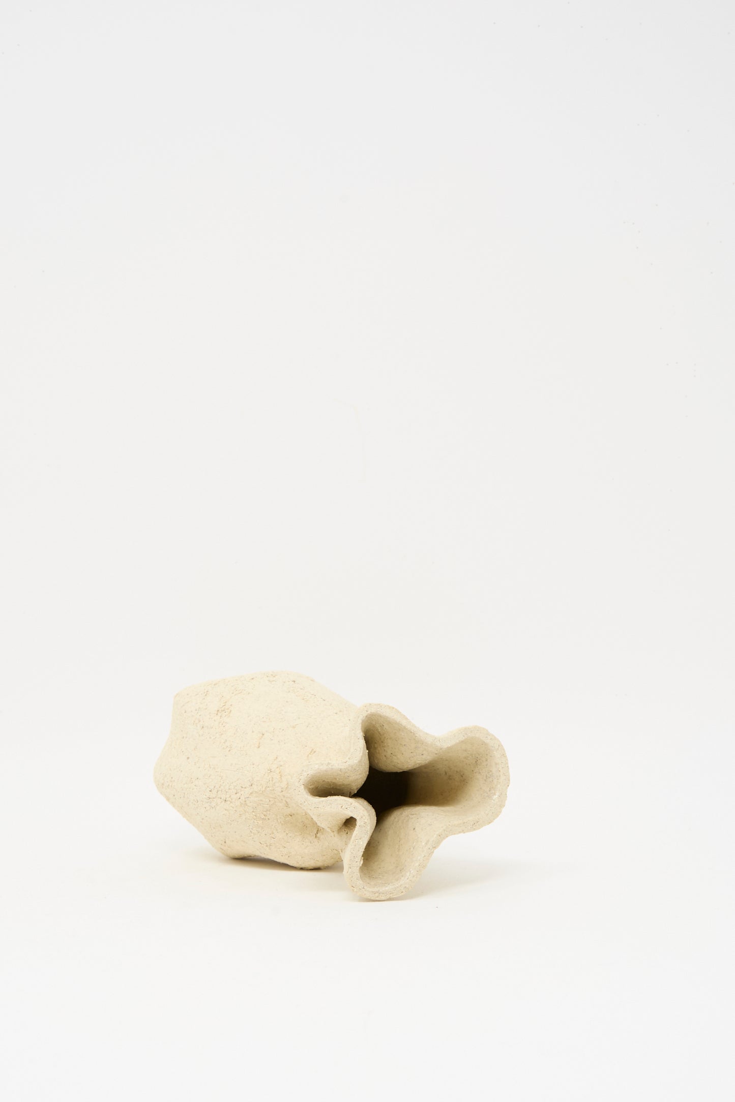 Textured Clay Folded Vessel I by Lost Quarry is a small, irregularly shaped beige handmade piece with a textured surface, displayed on a plain white background.