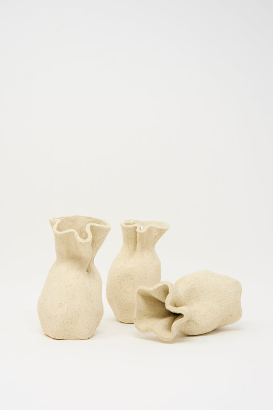 Textured Clay Folded Vessel I by Lost Quarry is a beige, handmade ceramic vase with an abstract, crumpled shape—ideal for displaying unique floral arrangements against any backdrop.