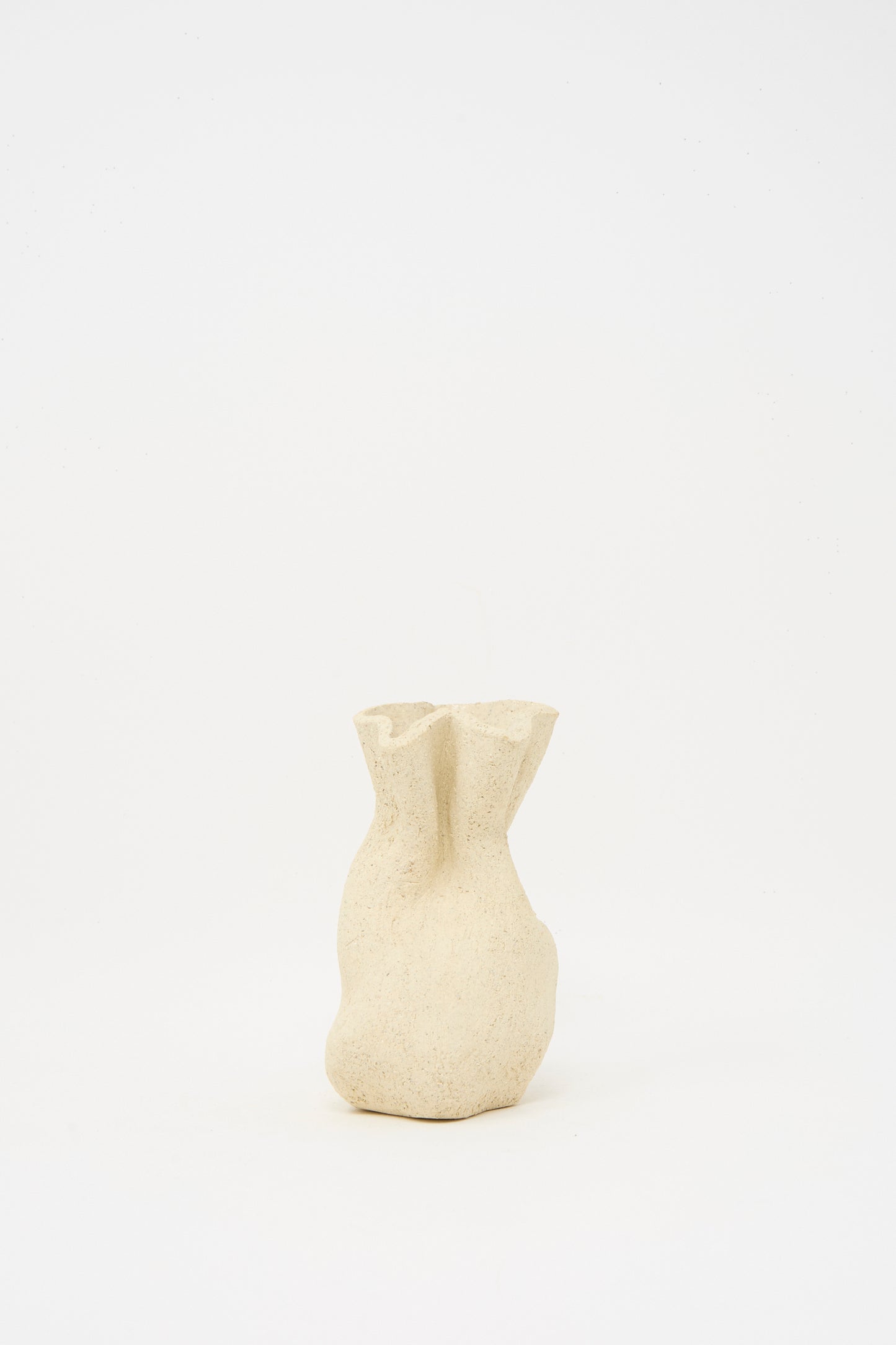 The Textured Clay Folded Vessel II by Lost Quarry is a small, beige ceramic vase with an organic, folded shape and textured finish—handmade to showcase unique floral arrangements against a simple white background.
