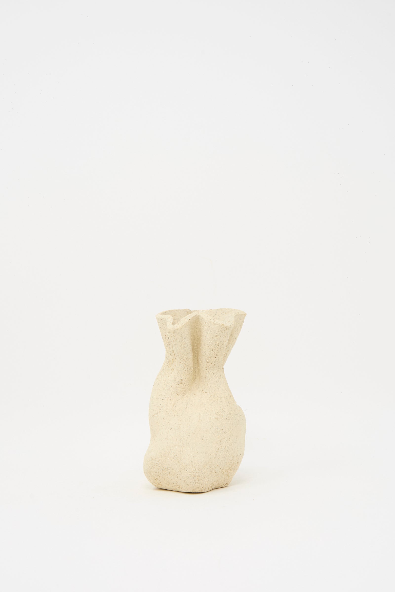 The Textured Clay Folded Vessel II by Lost Quarry is a small, beige ceramic vase with an organic, folded shape and textured finish—handmade to showcase unique floral arrangements against a simple white background.