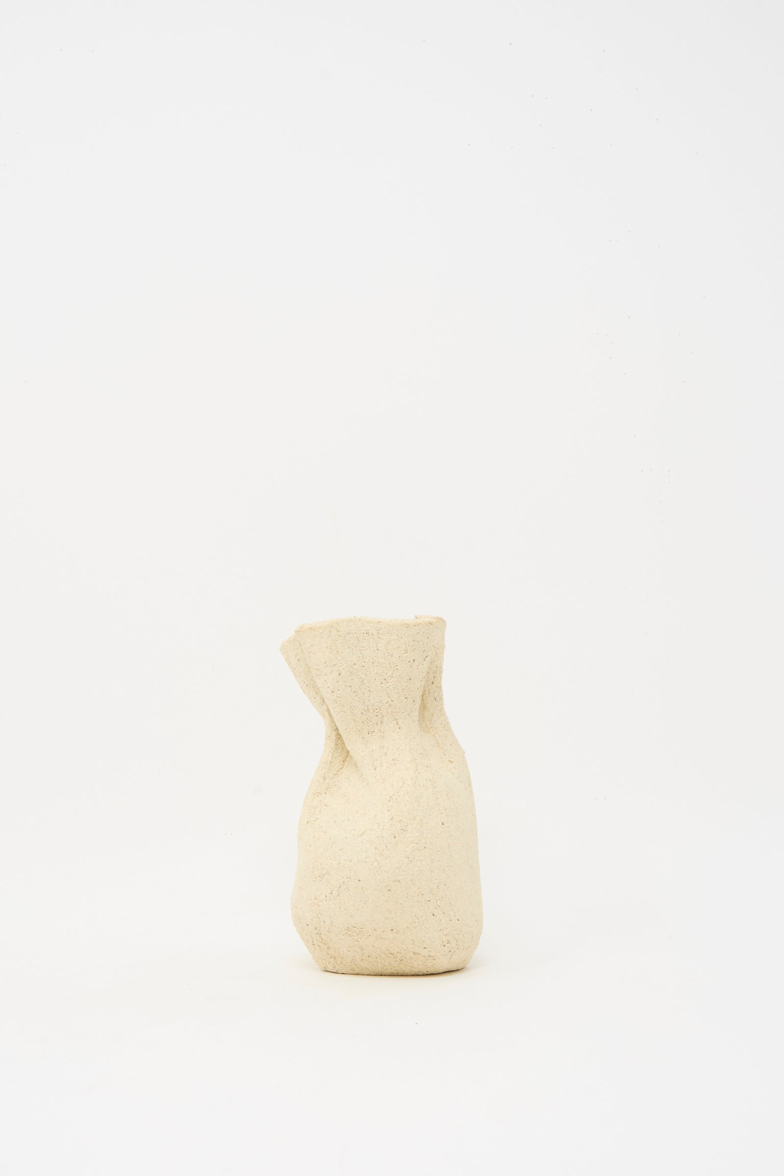 The Textured Clay Folded Vessel II by Lost Quarry is a small, beige, textured ceramic vase with an irregular, crumpled shape—handcrafted and perfect for displaying floral arrangements.