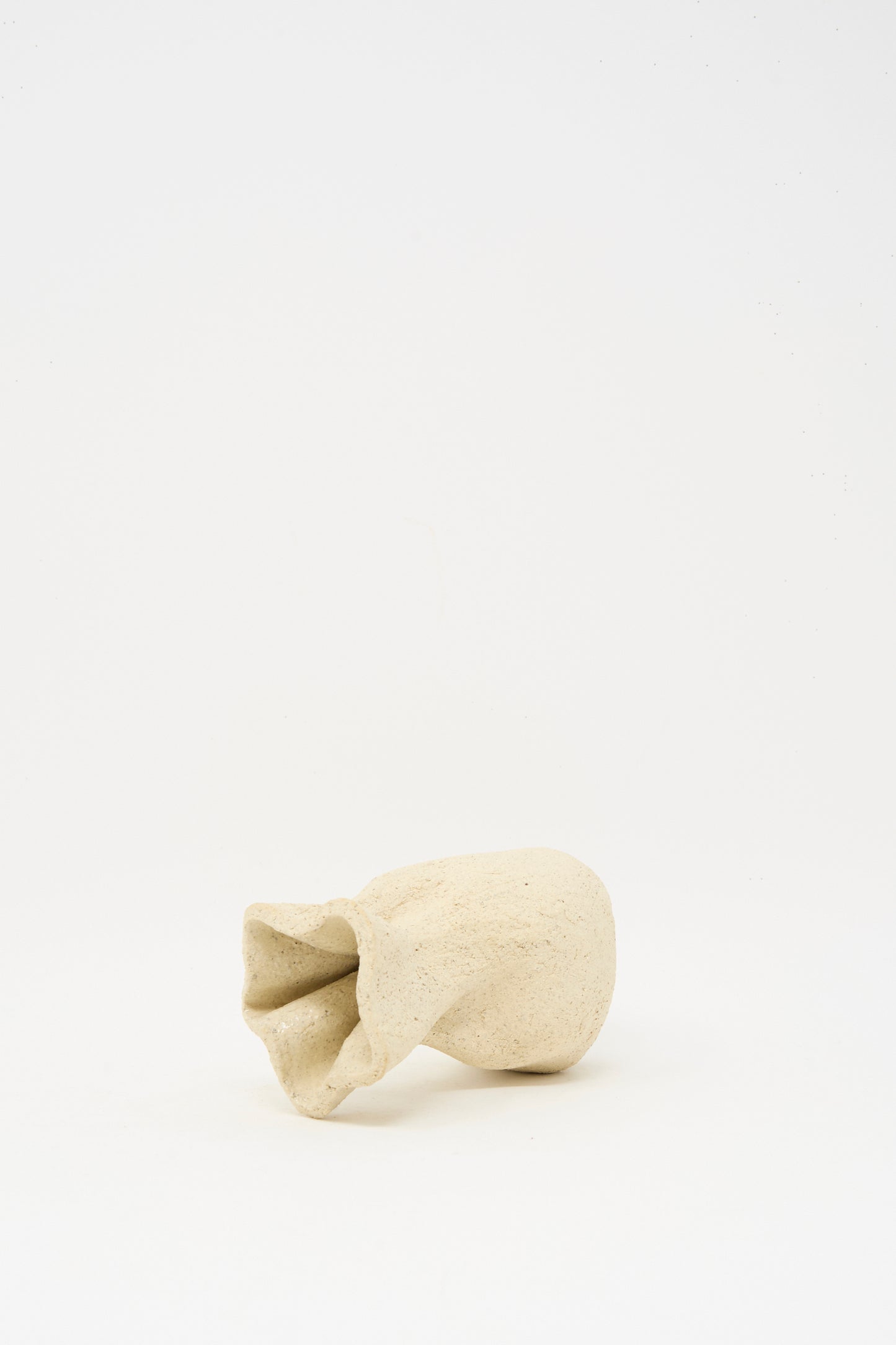 The Lost Quarry Textured Clay Folded Vessel II is a small, beige, abstract ceramic sculpture featuring a folded, textured opening and shown against a plain white background.