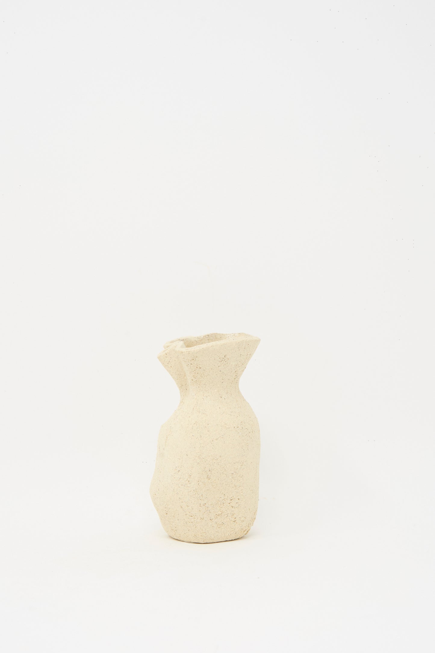 The Lost Quarry Textured Clay Folded Vessel III is a small, beige, handmade piece with a textured finish, uneven rim, and irregular shape—ideal for floral arrangements—shown against a plain white background.
