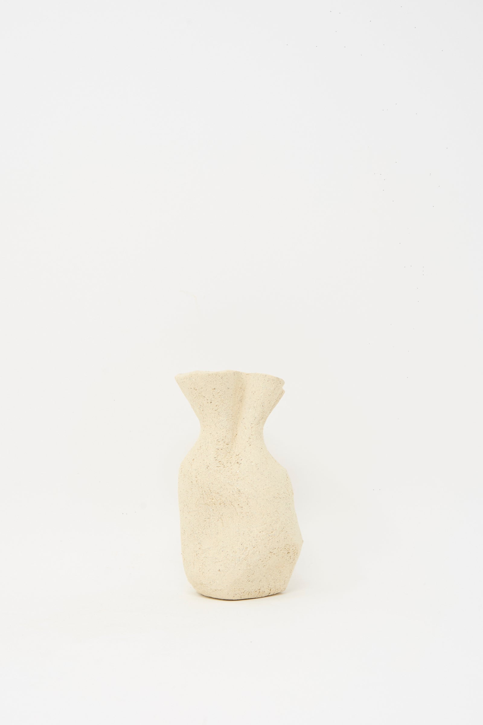 The Textured Clay Folded Vessel III by Lost Quarry is a beige, irregularly shaped ceramic vase with a rough texture, ideal for floral arrangements, crafted from white sculpture clay and shown against a plain white background.