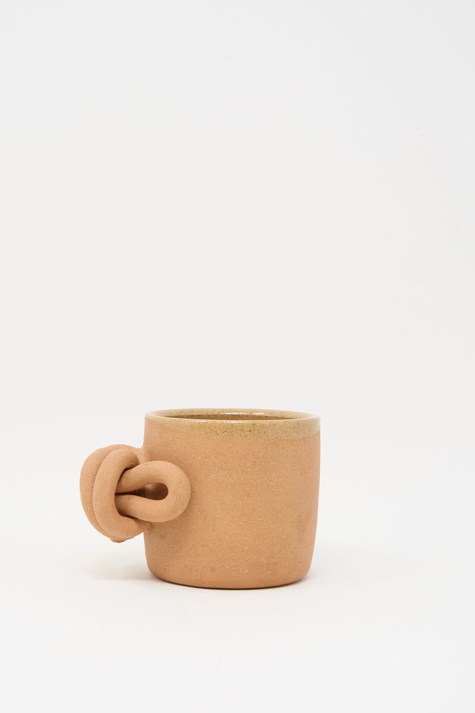 A Lost Quarry Overhand Knot Mug in Adobe, featuring a matte finish and unique knot-shaped handle, is displayed against a plain white background.
