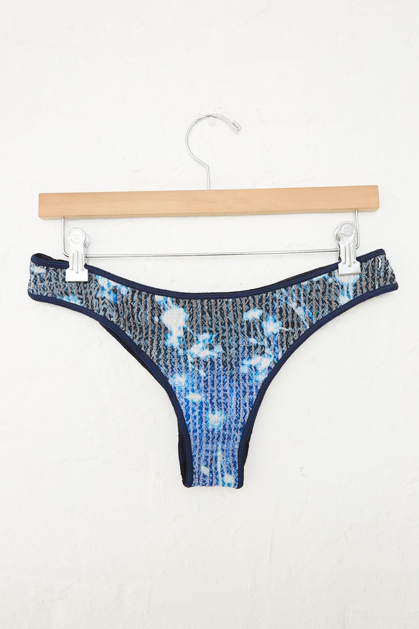 A Luna Del Pinal Jasmine Screen Printed Stretch Weave Crop Top Bikini in Midnight Blue hanging on a hanger.