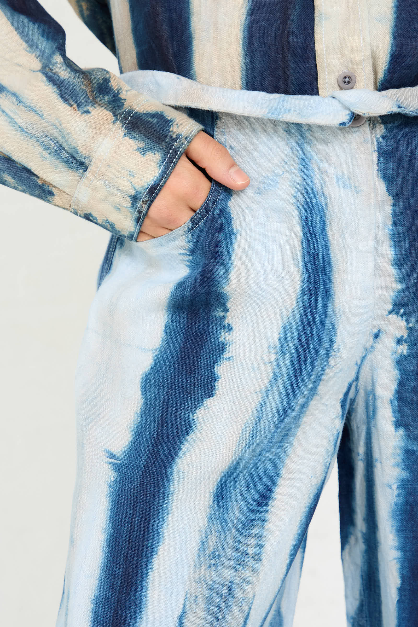 Person's hand in the pocket of Luna Del Pinal's Shibori Hemp Wide Leg Trouser in Faded Indigo, with a matching tie-dye shirt partially visible.