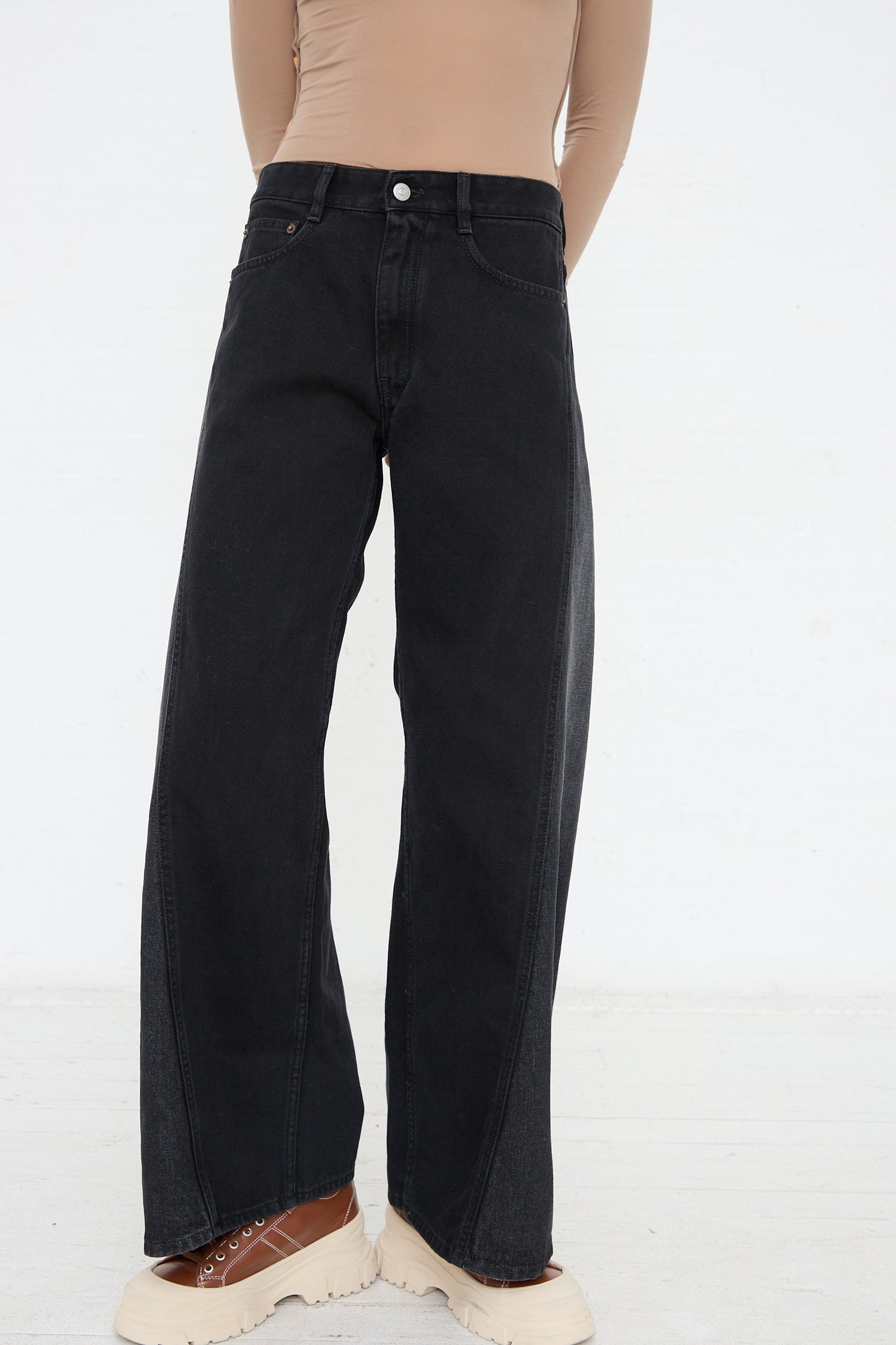 Person wearing high-waisted, wide-leg black MM6 5 Pocket Pant jeans and beige Maison Martin Margiela shoes.