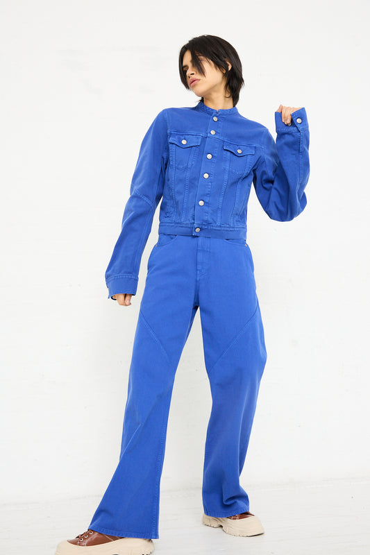 A woman in blue MM6 5 Pocket Pant stands confidently against a white background, looking to the side.